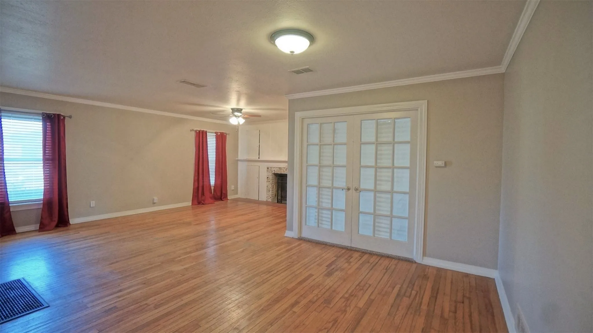 Unfurnished living room featuring light wood-style flooring, ceiling fan, a fireplace, and crown molding