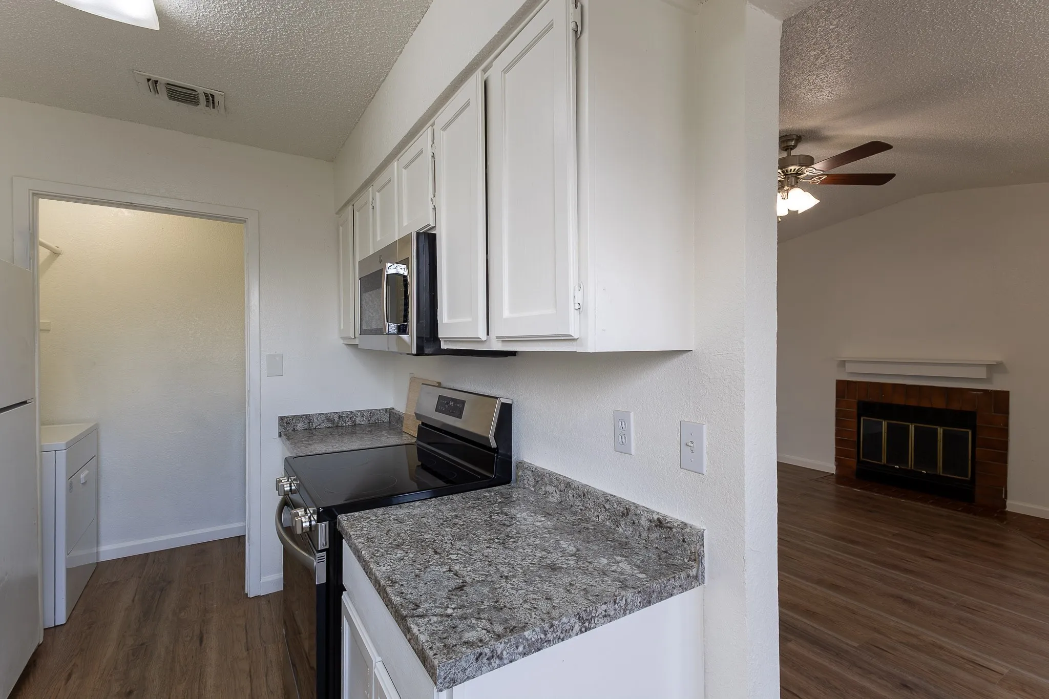 Kitchen featuring white cabinetry, grey speckled countertops, and stainless steel appliances
