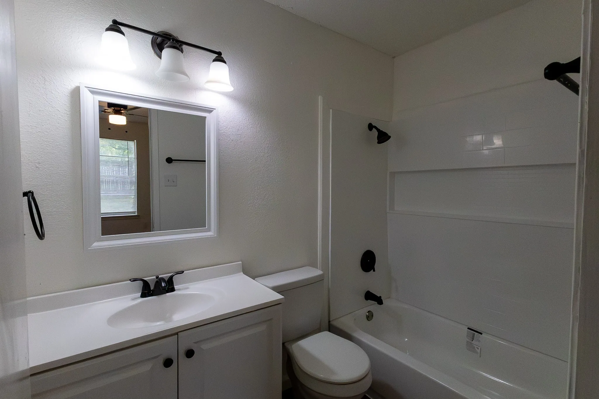 White vanity with integrated sink, matte black faucet, and framed mirror
