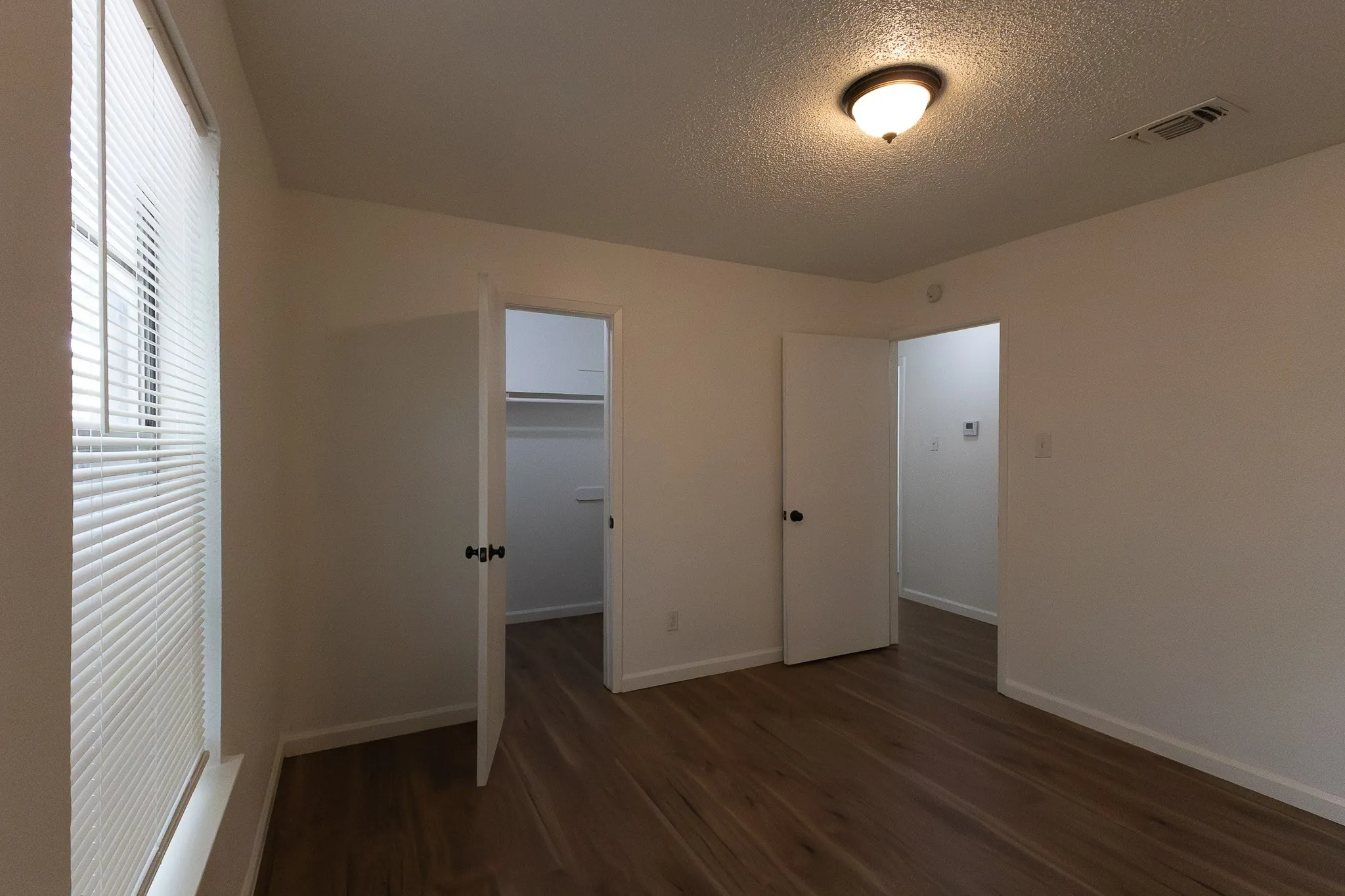 Wood-finish flooring throughout, white walls, and a window with horizontal​​‌​​​​‌​​‌‌​‌‌​​​‌‌​‌​‌​‌​​​‌​​ blinds