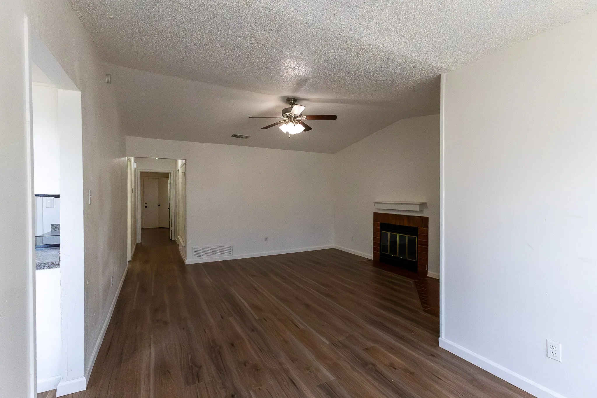 Open living area featuring wood-finish flooring and a vaulted ceiling
