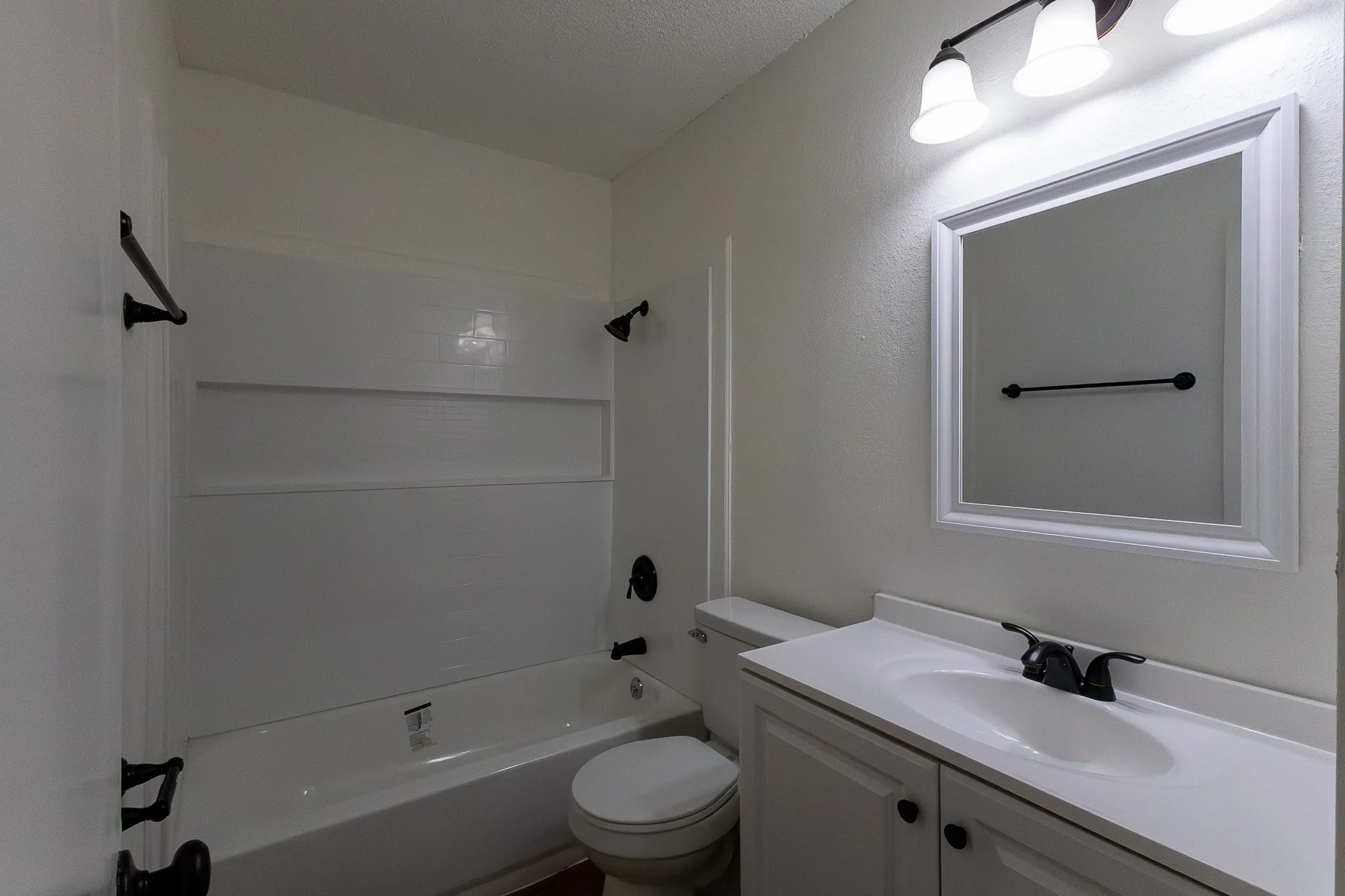 Bathroom featuring a white vanity with integrated sink, framed mirror, and a shower/tub combination with white surround