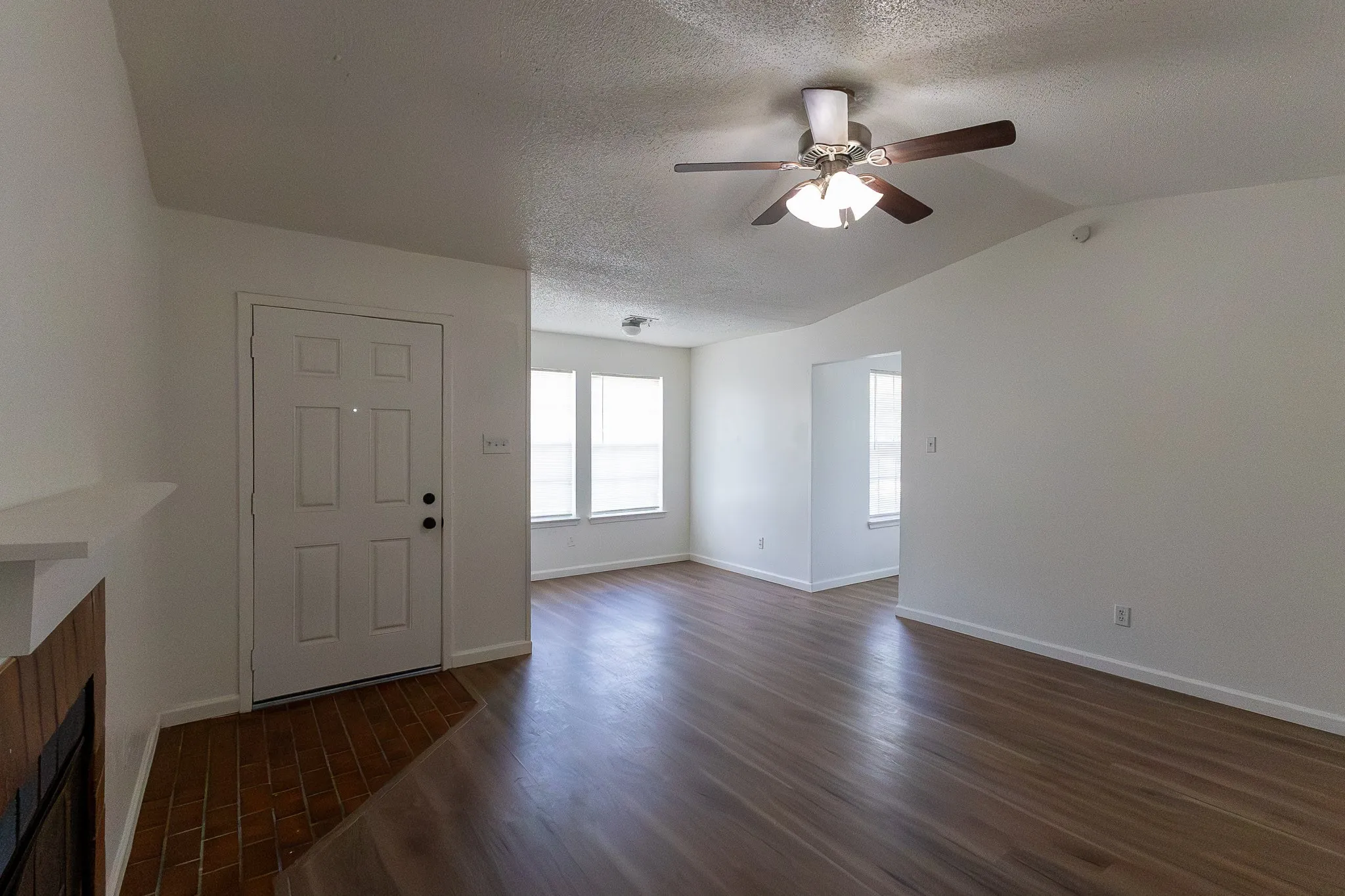 Wood-finish flooring throughout, white walls, and a ceiling fan with light fixture