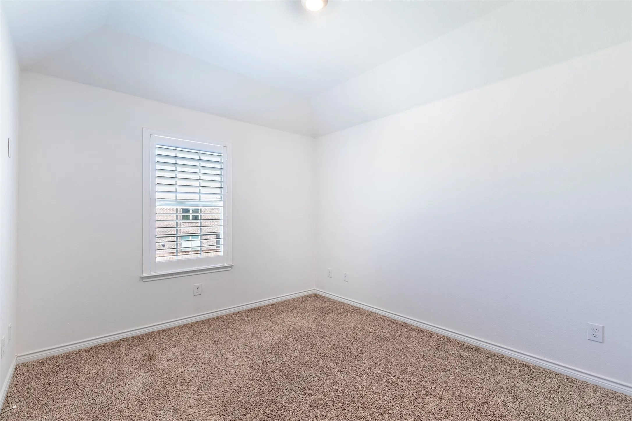 Neutral color palette, vaulted ceiling, recessed lighting, carpet flooring, window with blinds