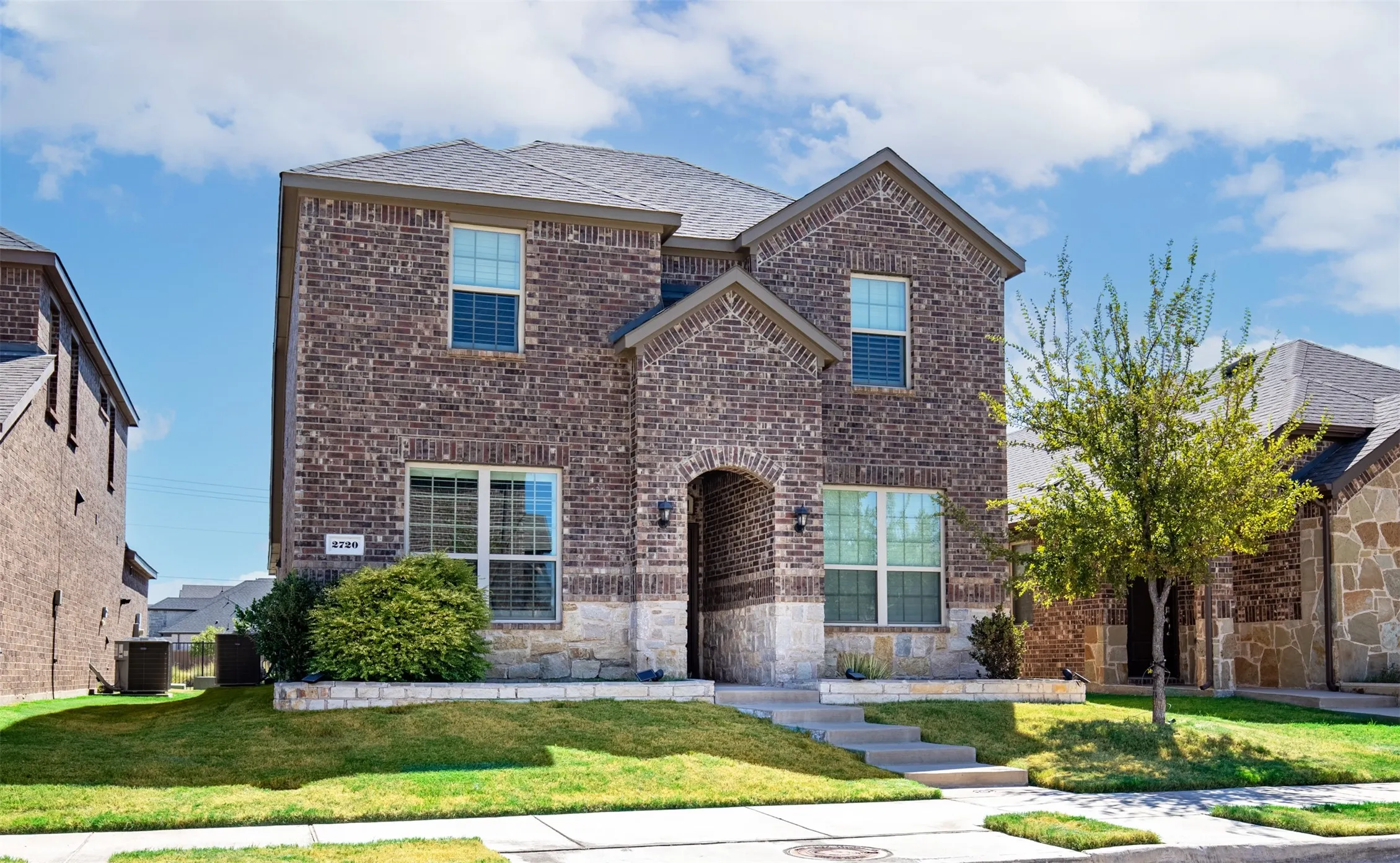 Two-story brick exterior with stone accents and arched entryway