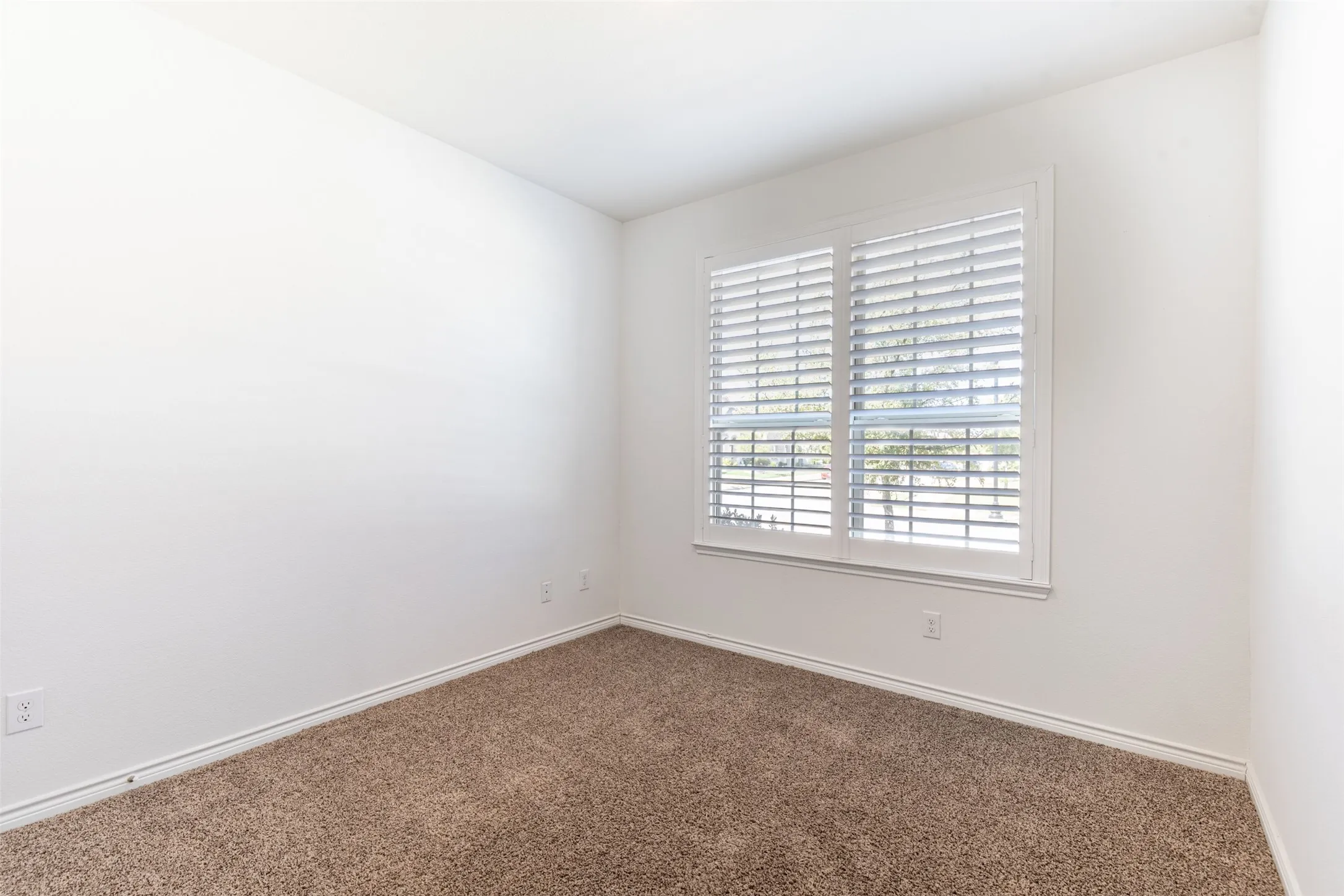 White walls, white window trim, and a window with white plantation shutters