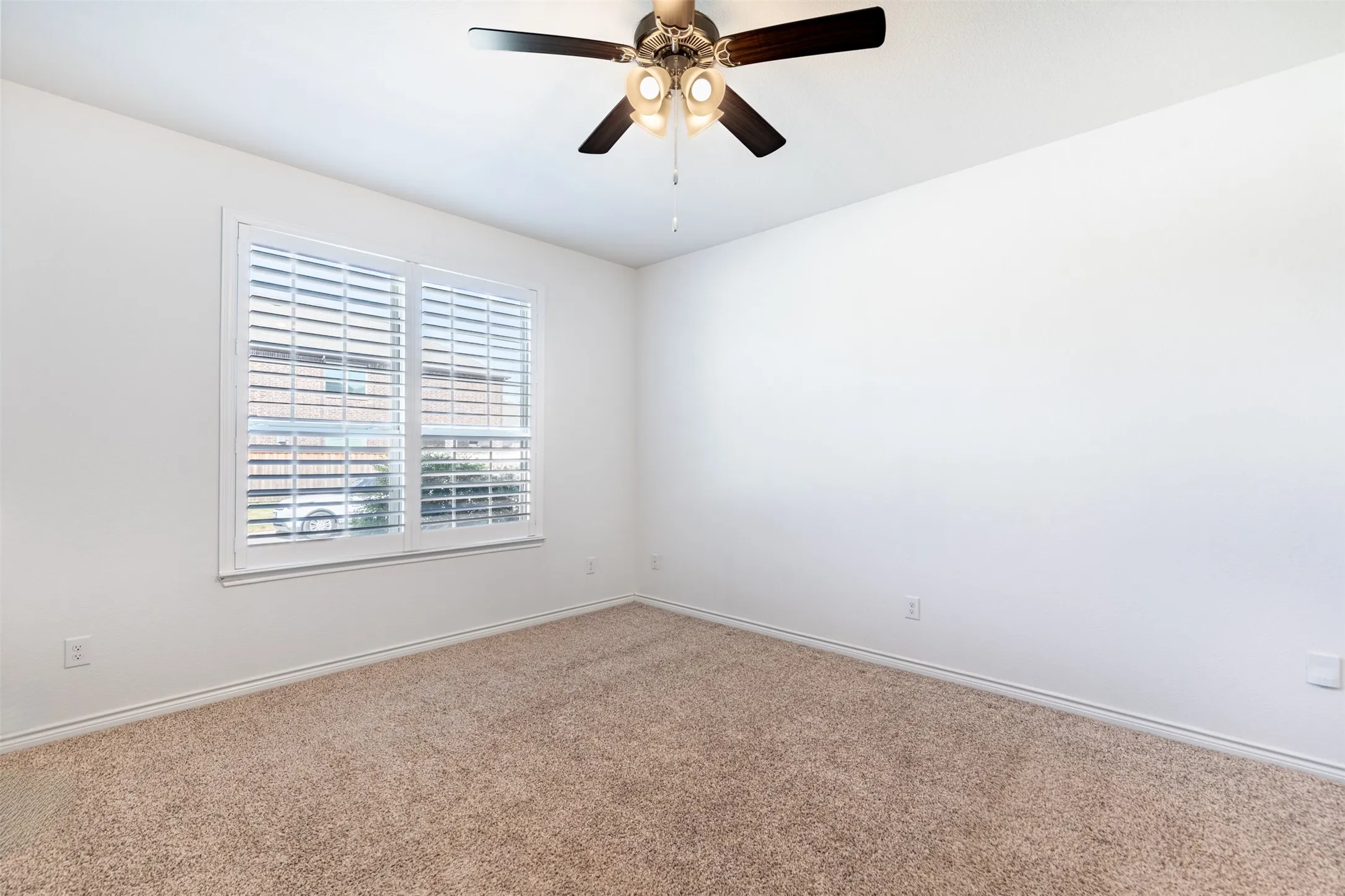 Neutral-toned carpeting, white walls, and a window with plantation shutters