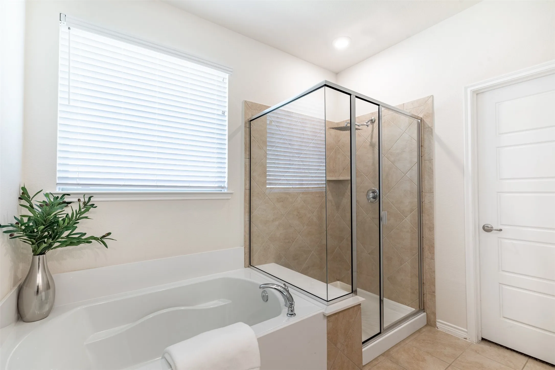 Built-in soaking tub, glass-enclosed shower with tiled walls, tiled flooring, and a window with blinds