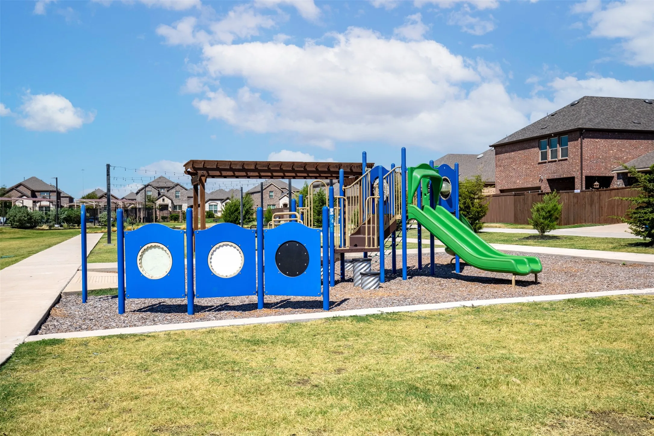 Community playground featuring a slide, play structure, and overhead pergola
