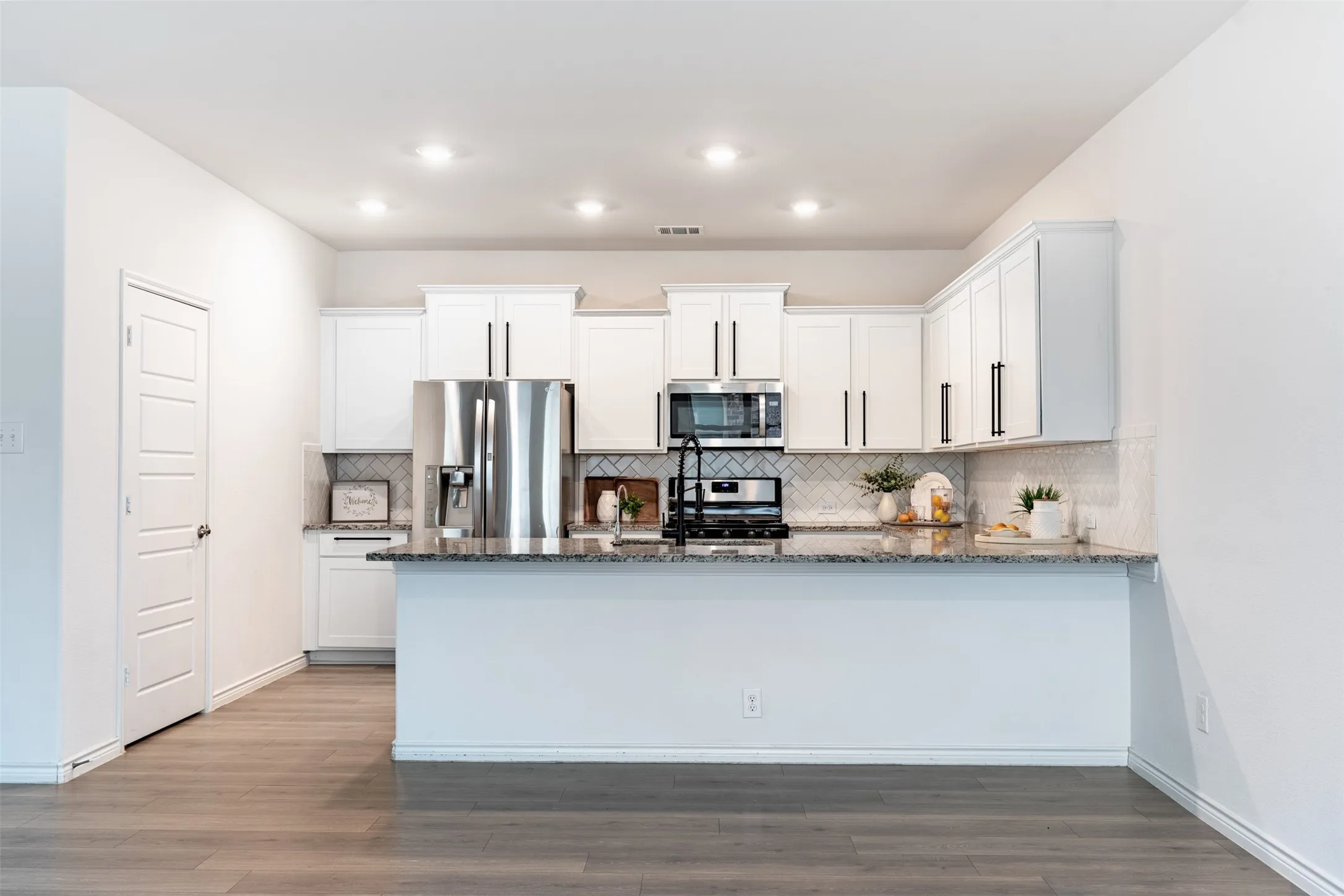 Kitchen featuring white cabinetry, stainless steel appliances, granite countertops, a tiled backsplash, and recessed lighting