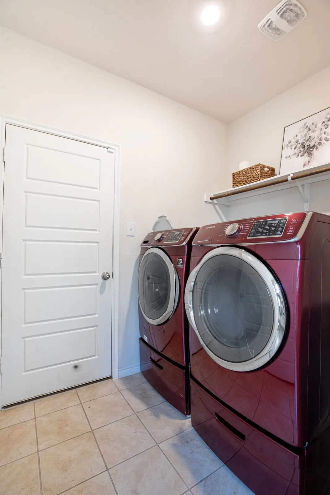 Tile flooring, white paneled door, ceiling-mounted light fixture, and wall-mounted shelving