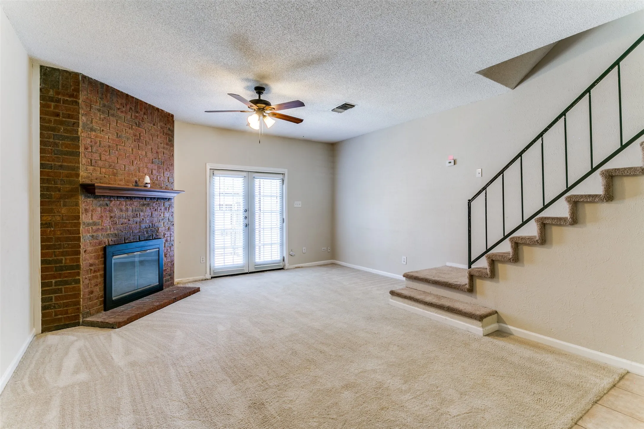 Brick fireplace with wood mantel, glass-front fireplace insert, and brick hearth