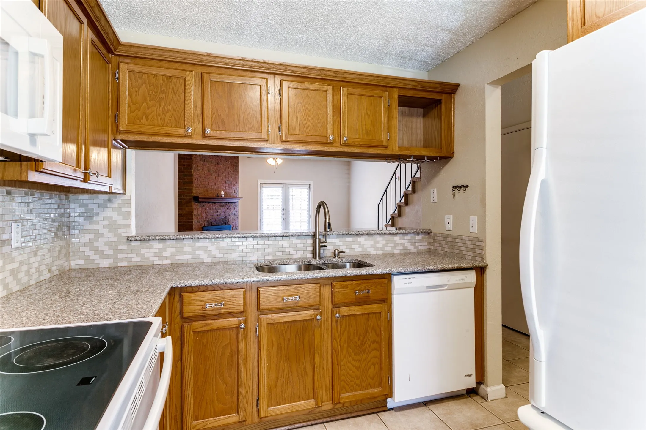 Kitchen featuring wood cabinetry, stone-finish countertops, subway tile backsplash, and stainless steel sink
