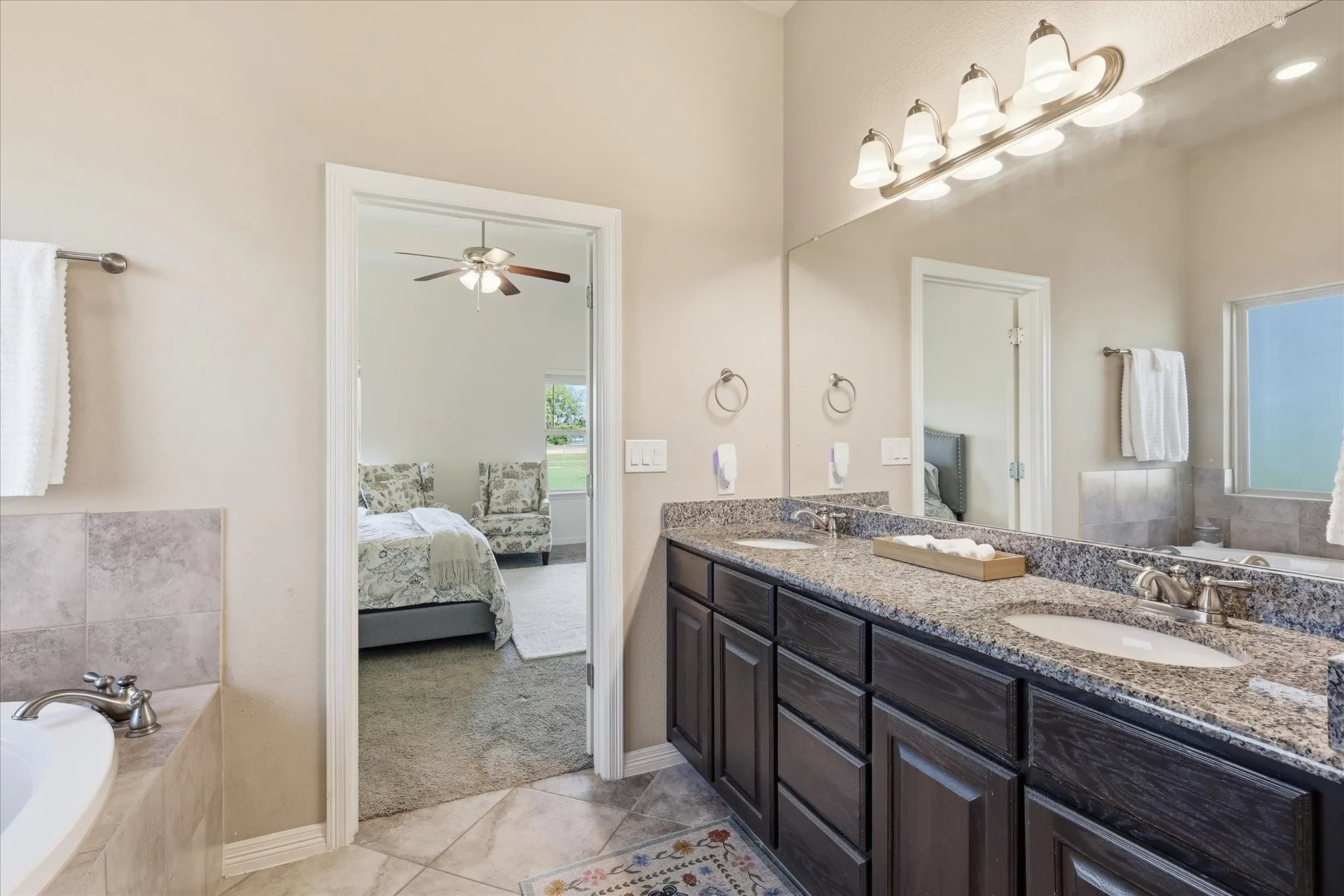 Dual vanity with granite countertops, undermount sinks, and dark wood-finish cabinetry