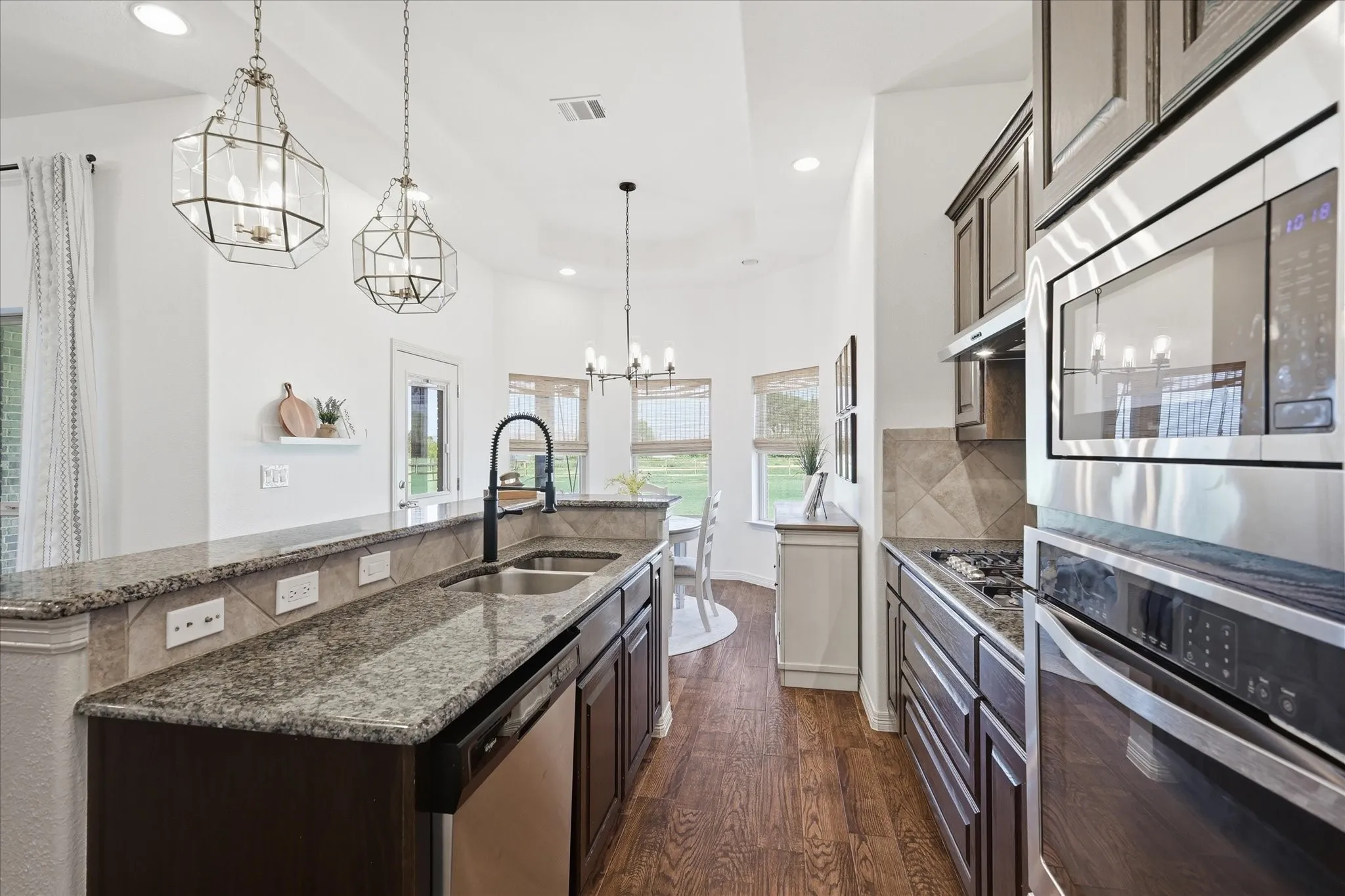 Kitchen featuring dark wood-finish cabinetry, stainless steel appliances, granite countertops, and wood-finish flooring