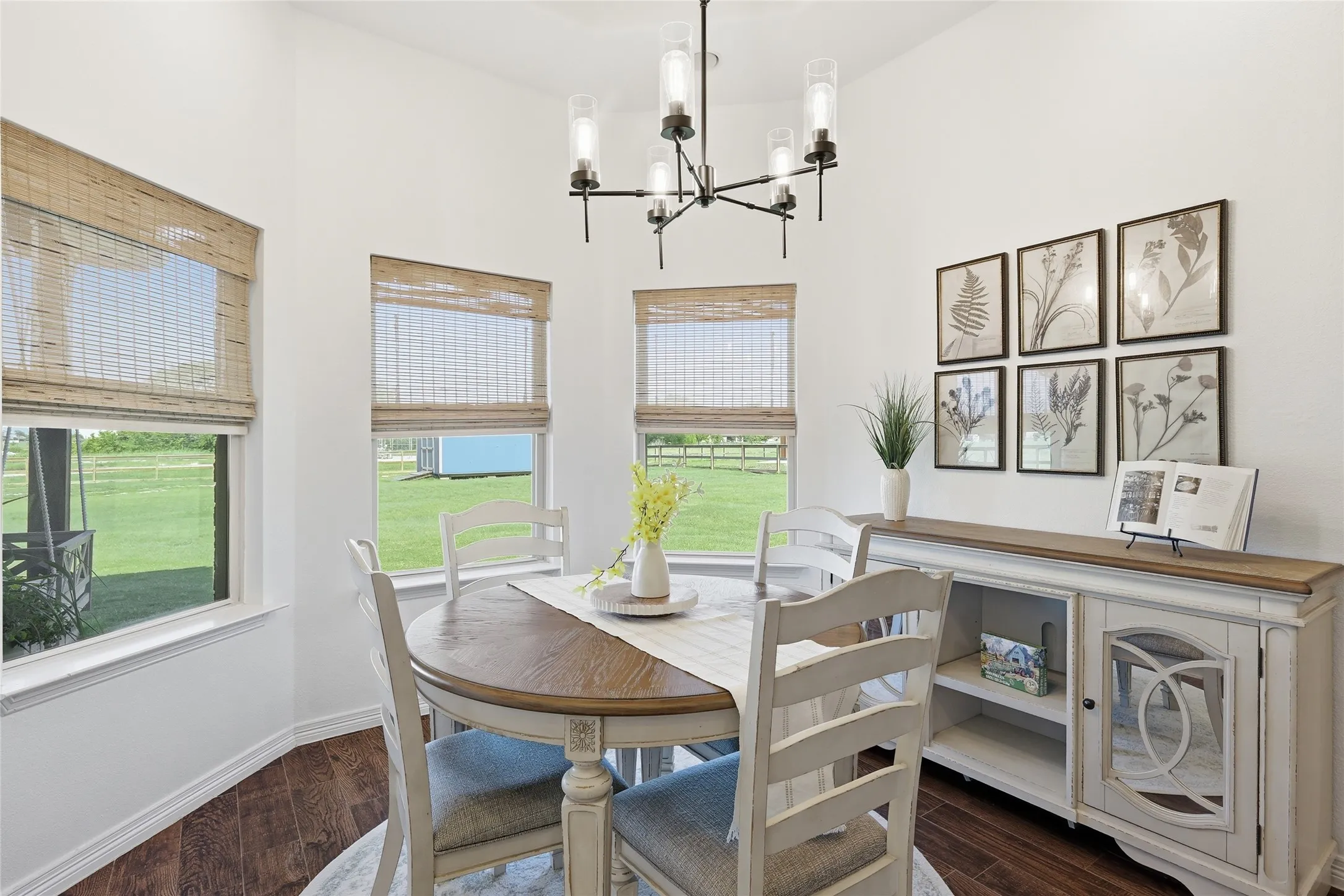 Vaulted ceiling with a chandelier light fixture, multiple windows with blinds, built-in shelving, and wood-finish flooring
