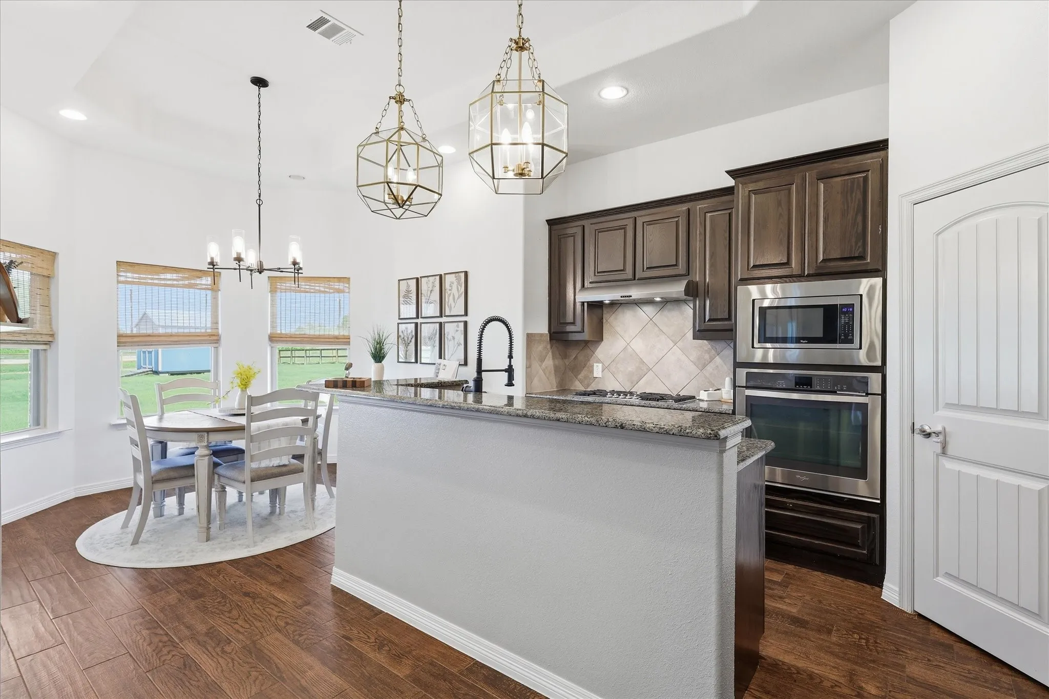 Kitchen featuring dark wood cabinetry, stainless steel appliances, a tiled backsplash, wood-finish flooring, and a dining nook with a chandelier