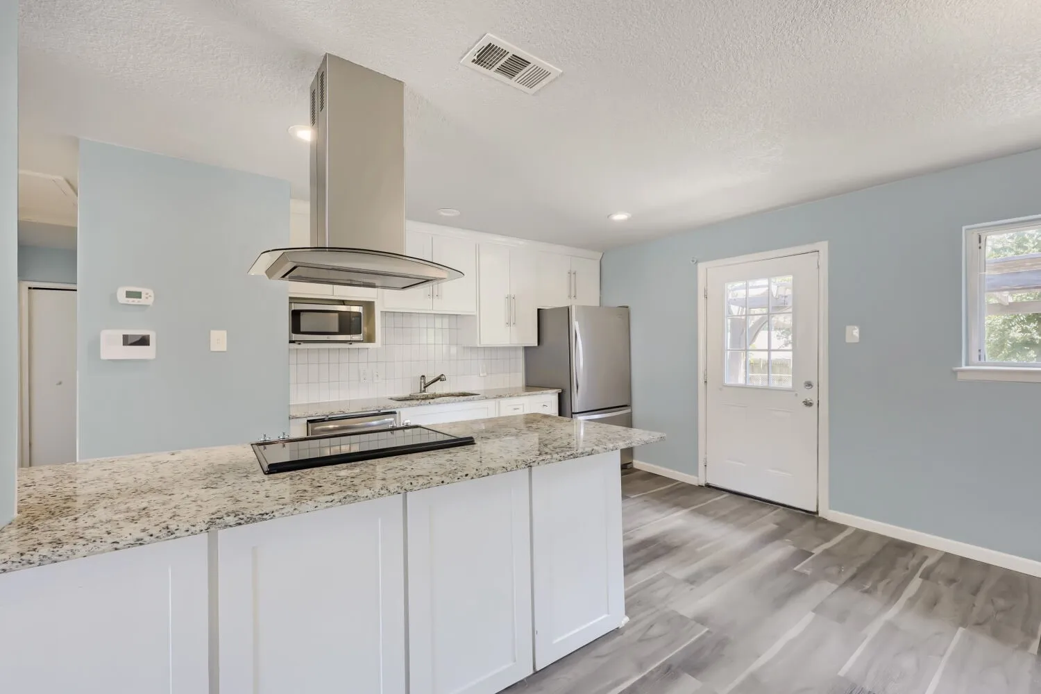 Kitchen featuring a built-in cooktop, stainless steel range hood, white cabinetry, granite countertops, and wood-finish flooring