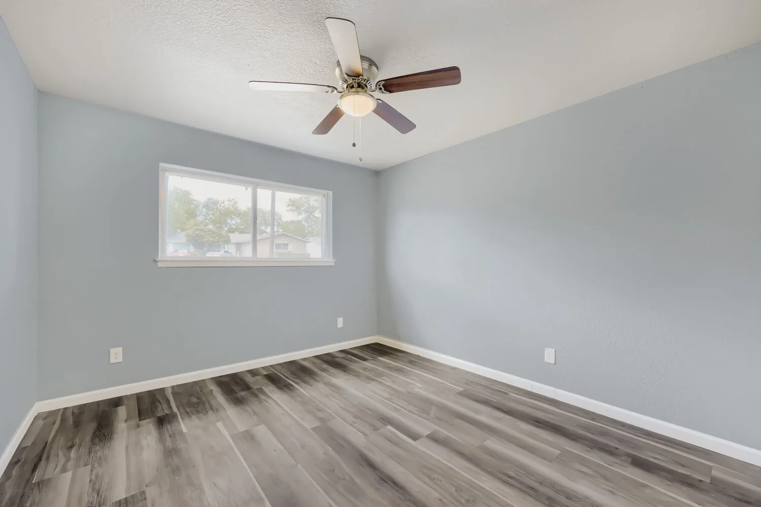 Interior space featuring a ceiling fan with integrated lighting, wood-finish flooring, and a large window
