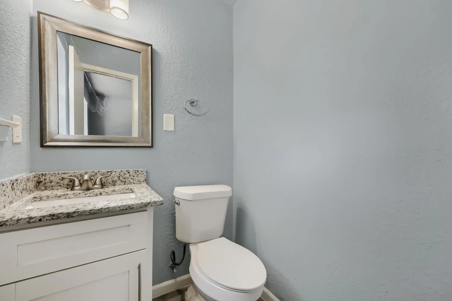 White vanity with brushed nickel hardware, granite-style countertop, and an undermount sink