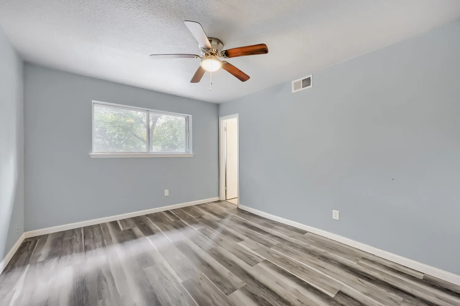 Wood-finish flooring with a neutral paint palette and ceiling fan
