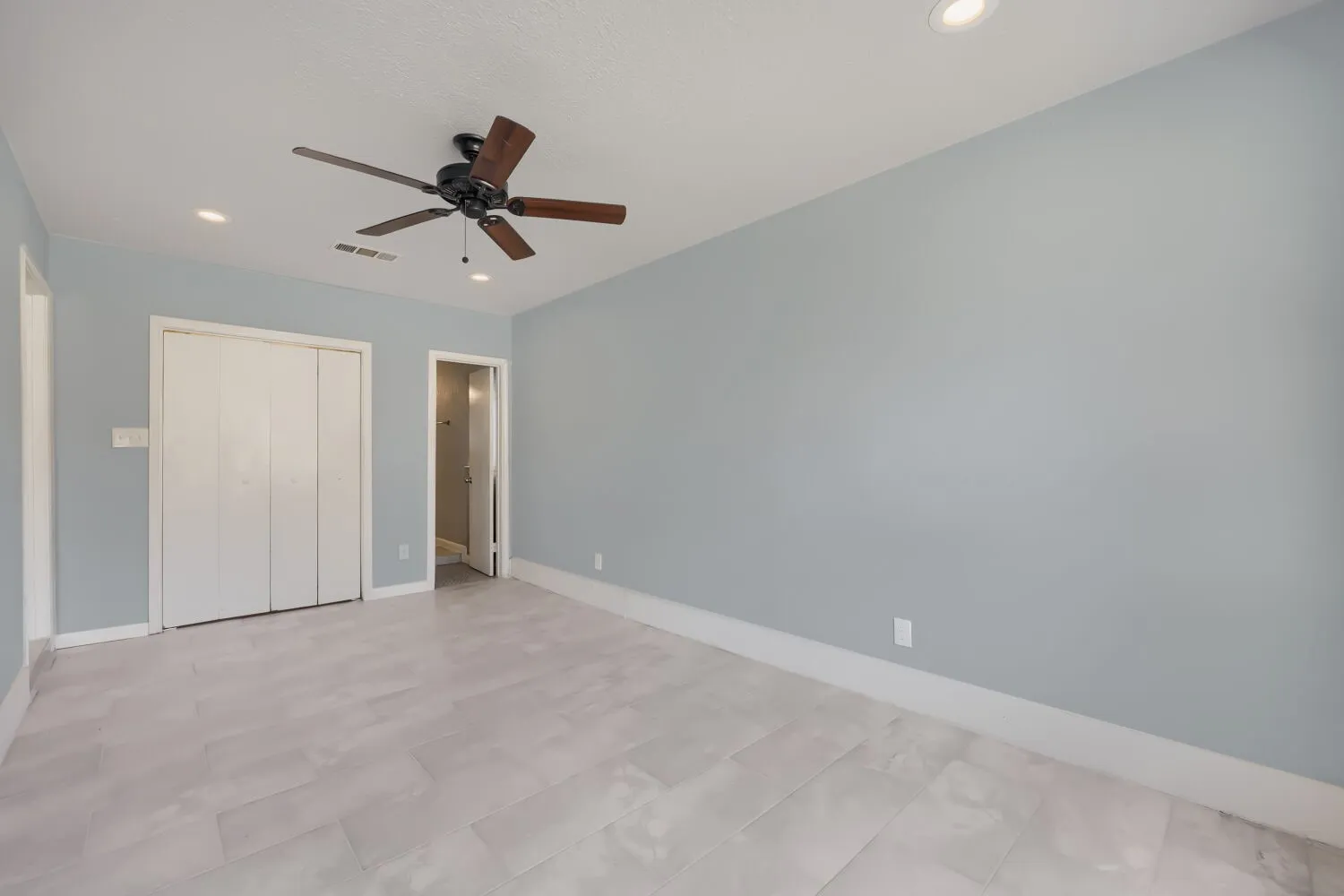 Recessed lighting, ceiling fan with wood-finish blades, light blue wall paint, white trim, and light-toned tile flooring