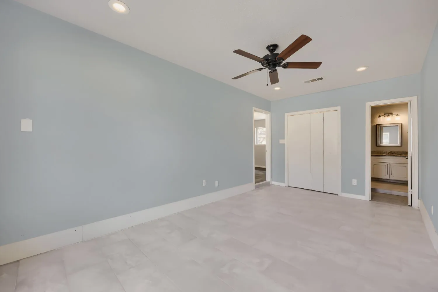 Spacious room featuring light blue walls, recessed lighting, a ceiling fan, and light-toned tile flooring