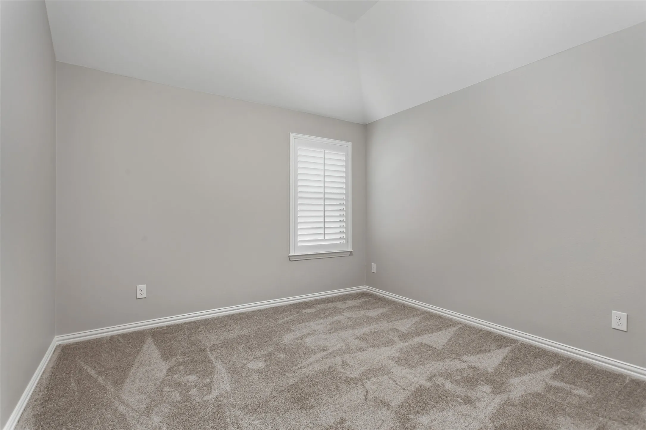 One of 3 secondary bedrooms with new 2026 carpet, fresh 2026 paint, and a window with plantation shutters.
Vaulted ceiling line and generous closet space.