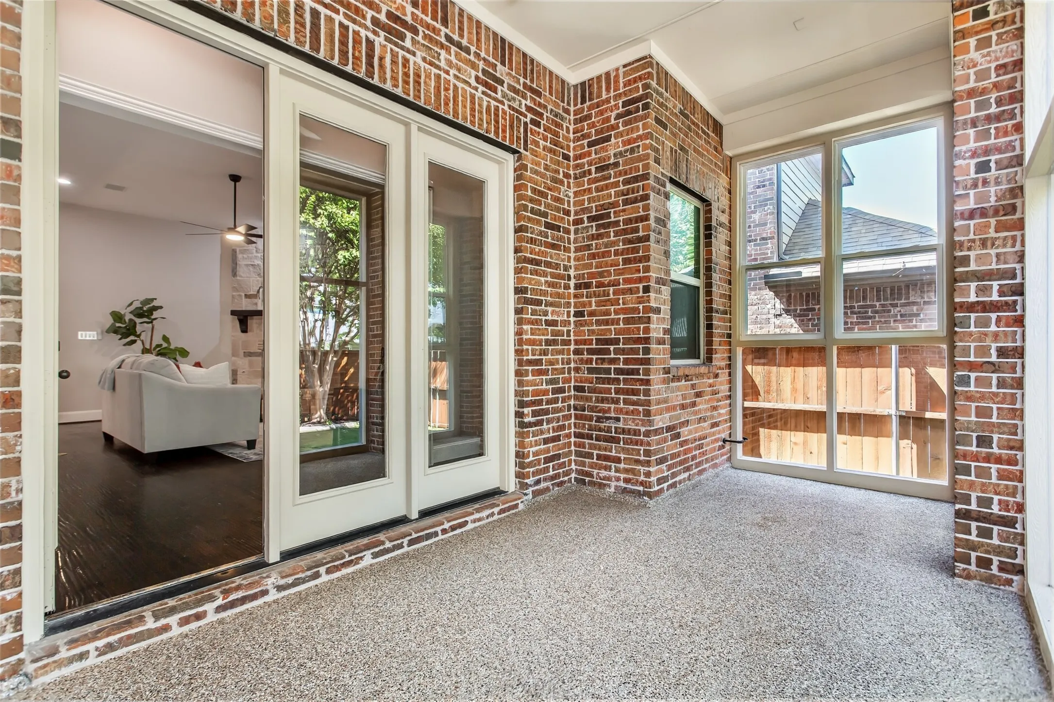 Brick-walled sunroom with epoxy flooring, a ceiling fan, and French doors back to the family room.
Windows on two sides bring in natural light.
