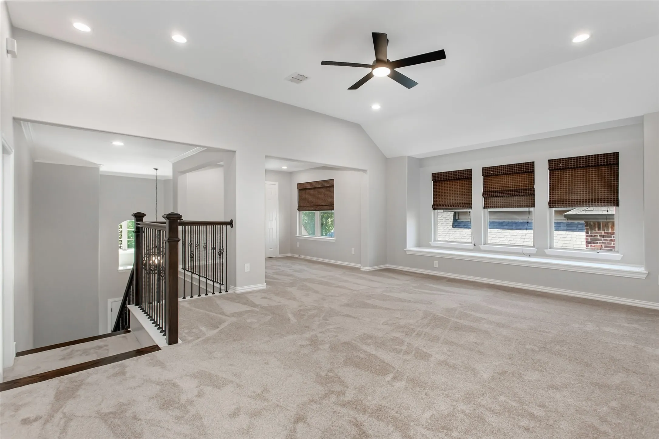 Upstairs game room with a vaulted ceiling, recessed lighting, and a new 2026 ceiling fan. A row of three
windows with a deep sill and an open overlook to the foyer staircase.