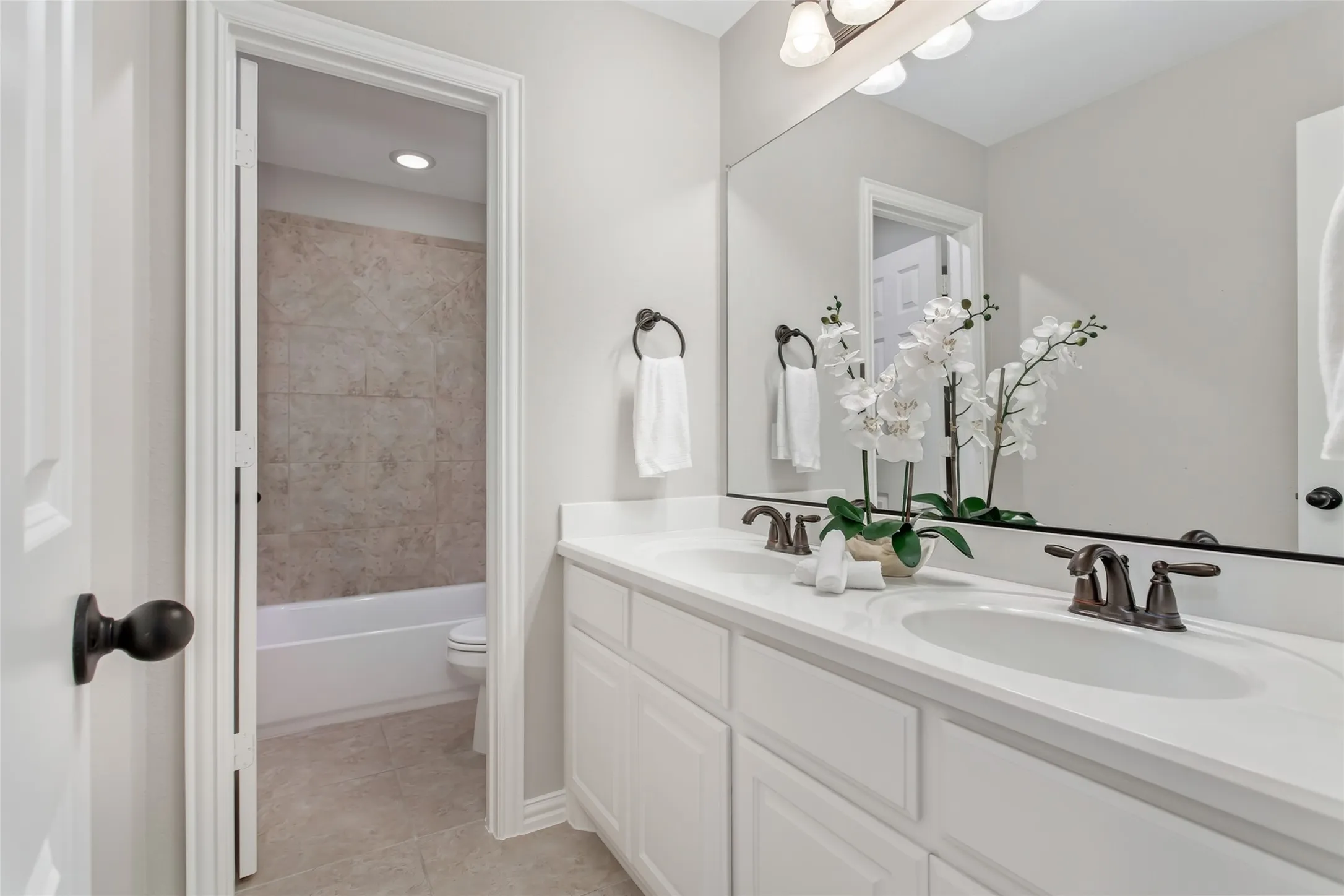 Dual-sink vanity with white cabinetry and oil-rubbed bronze faucets. A separate room holds the tub and
shower combination and toilet.