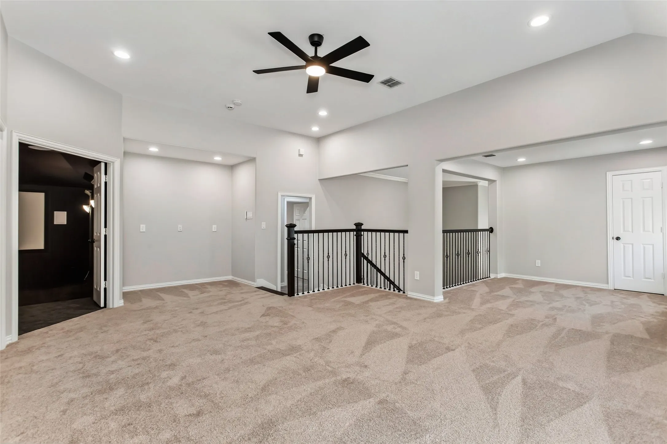 Open game room at the top of the stairs with wrought iron railings, recessed lighting, and a new 2026 ceiling
fan. Double doors on the left open to the media room.