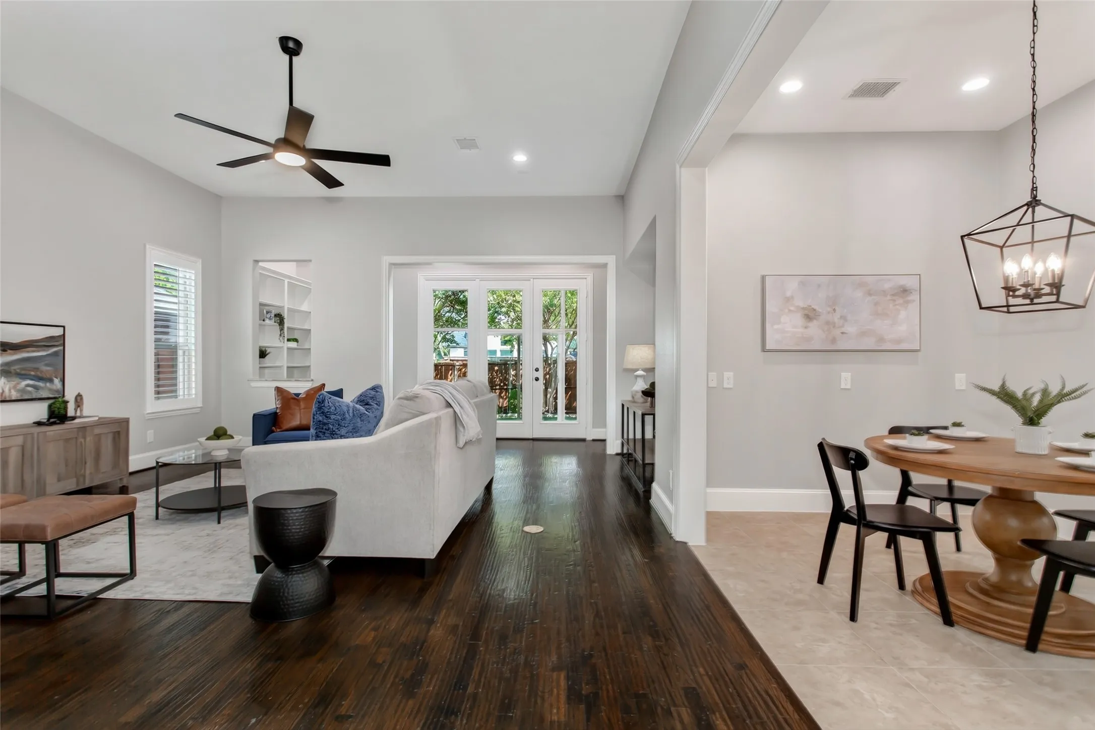 Family room with hand-scraped hardwoods, a wall of French doors to the enclosed sunroom, and a
built-in bookcase niche. The breakfast area connects on the right under a new 2026 lantern pendant.