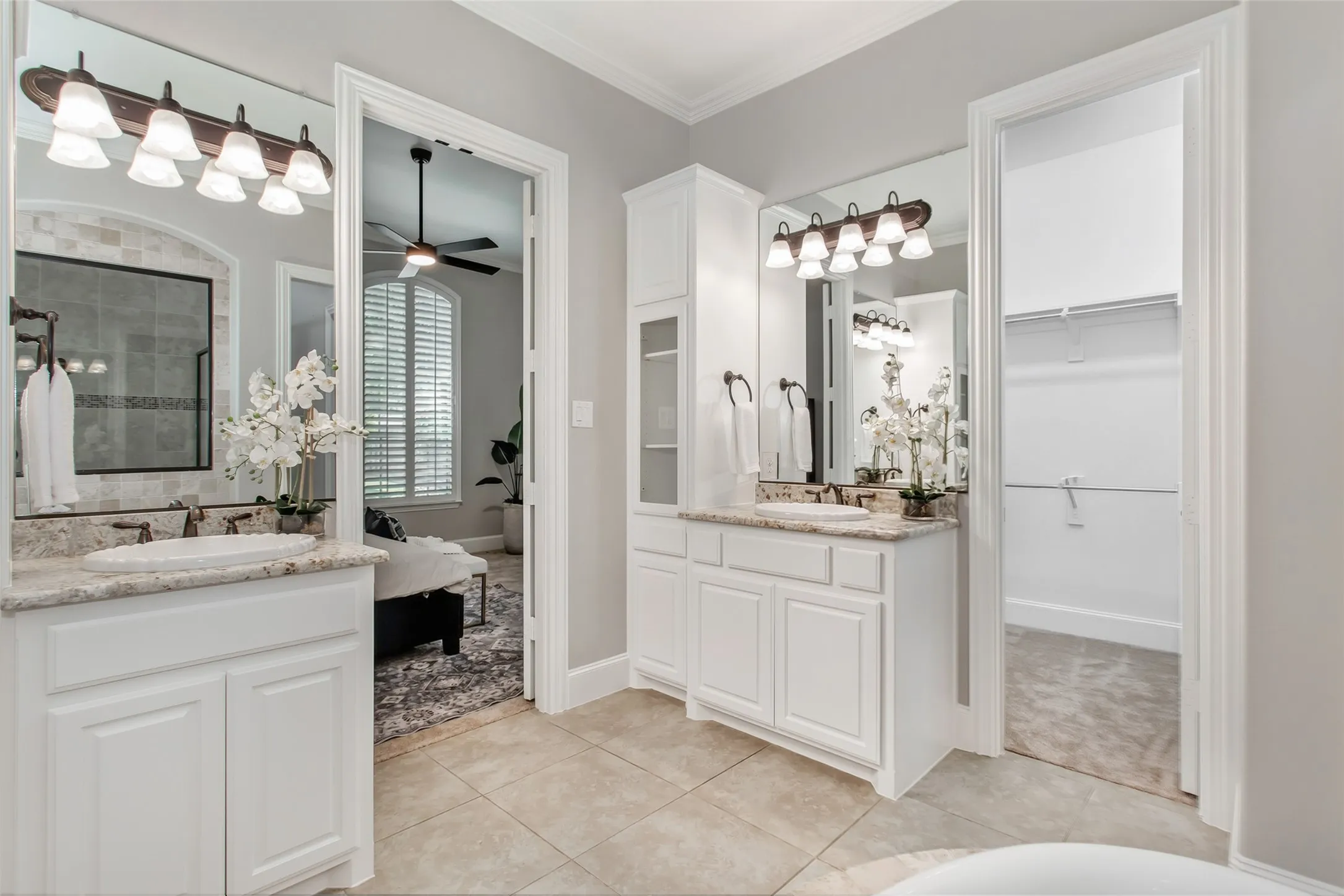 Two separate vanities with granite counters and a linen tower with open shelving. Doorways to the
walk-in closet and the primary bedroom.