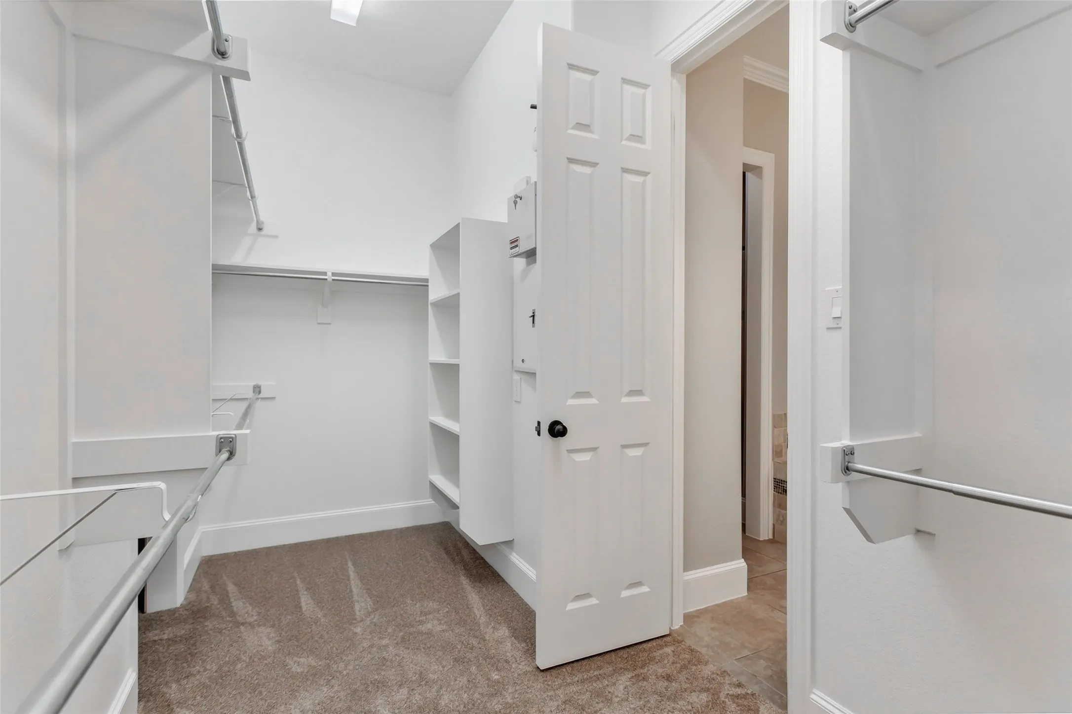 Walk-in closet with double hanging rods, built-in shelving, and new 2026 carpet. Opens directly to the
primary bath.