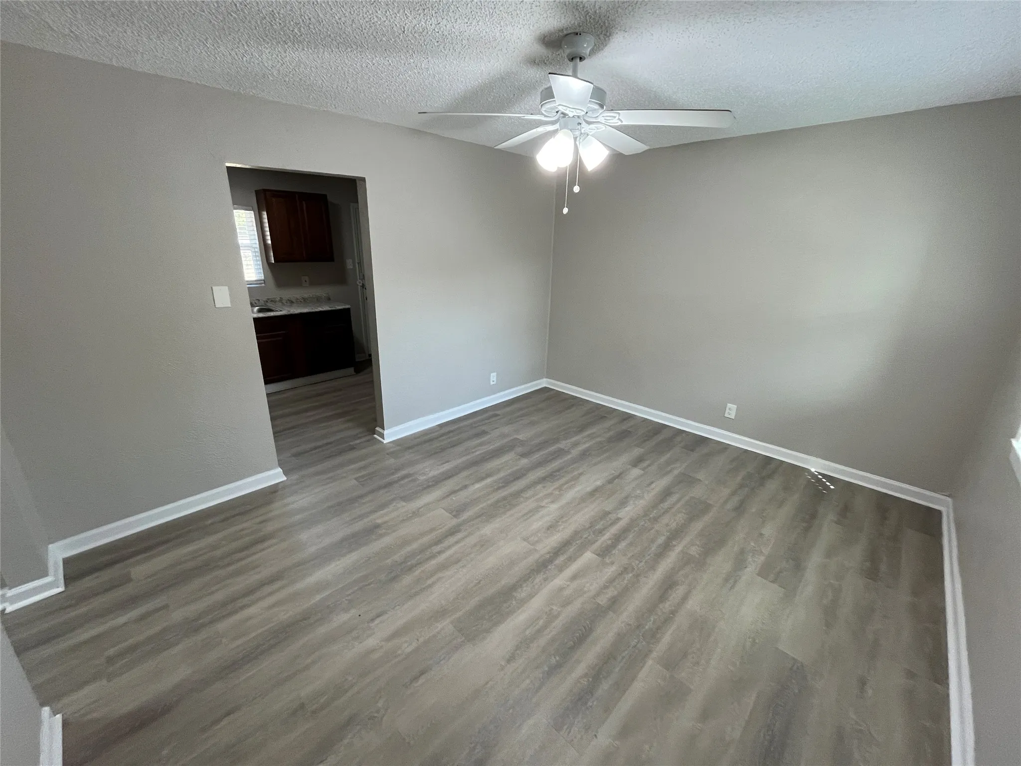 Wood-finish flooring with light gray walls, white trim, and a ceiling fan with integrated lighting