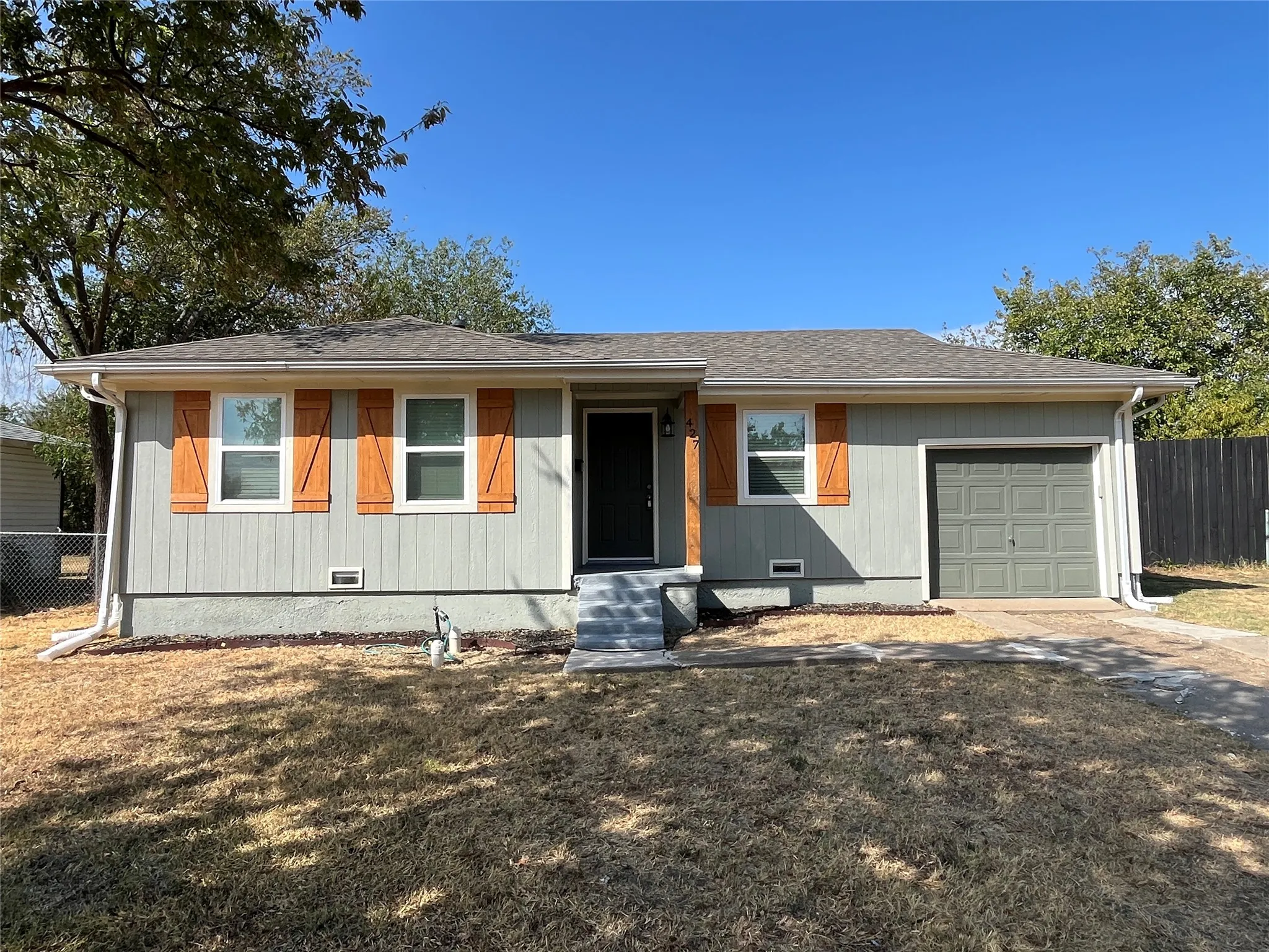Exterior featuring horizontal siding, wood-look window shutters, a dark entry door, and an attached garage with a panel door