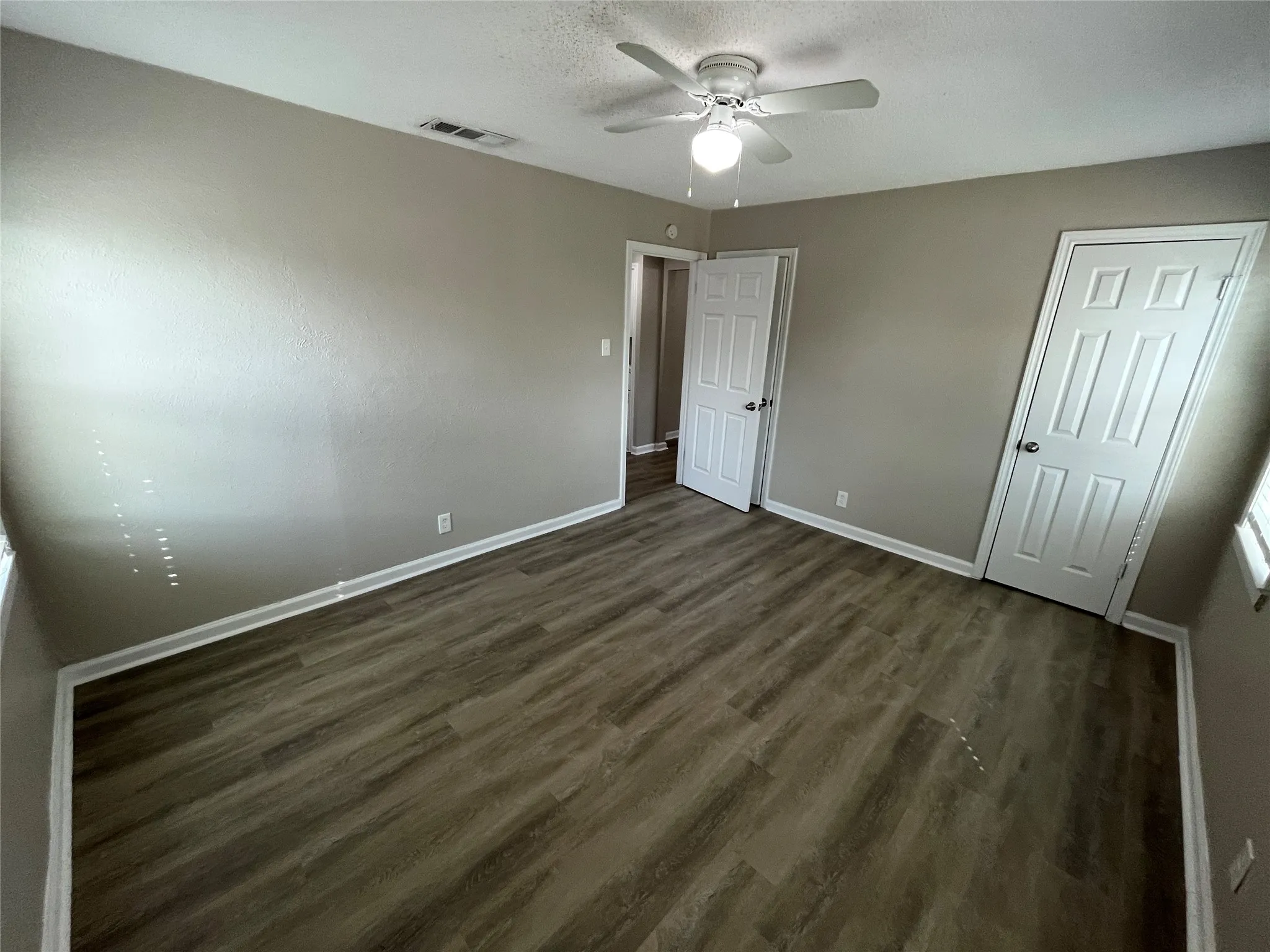 Wood-finish flooring with white trim, a ceiling fan with integrated lighting, and neutral wall tones