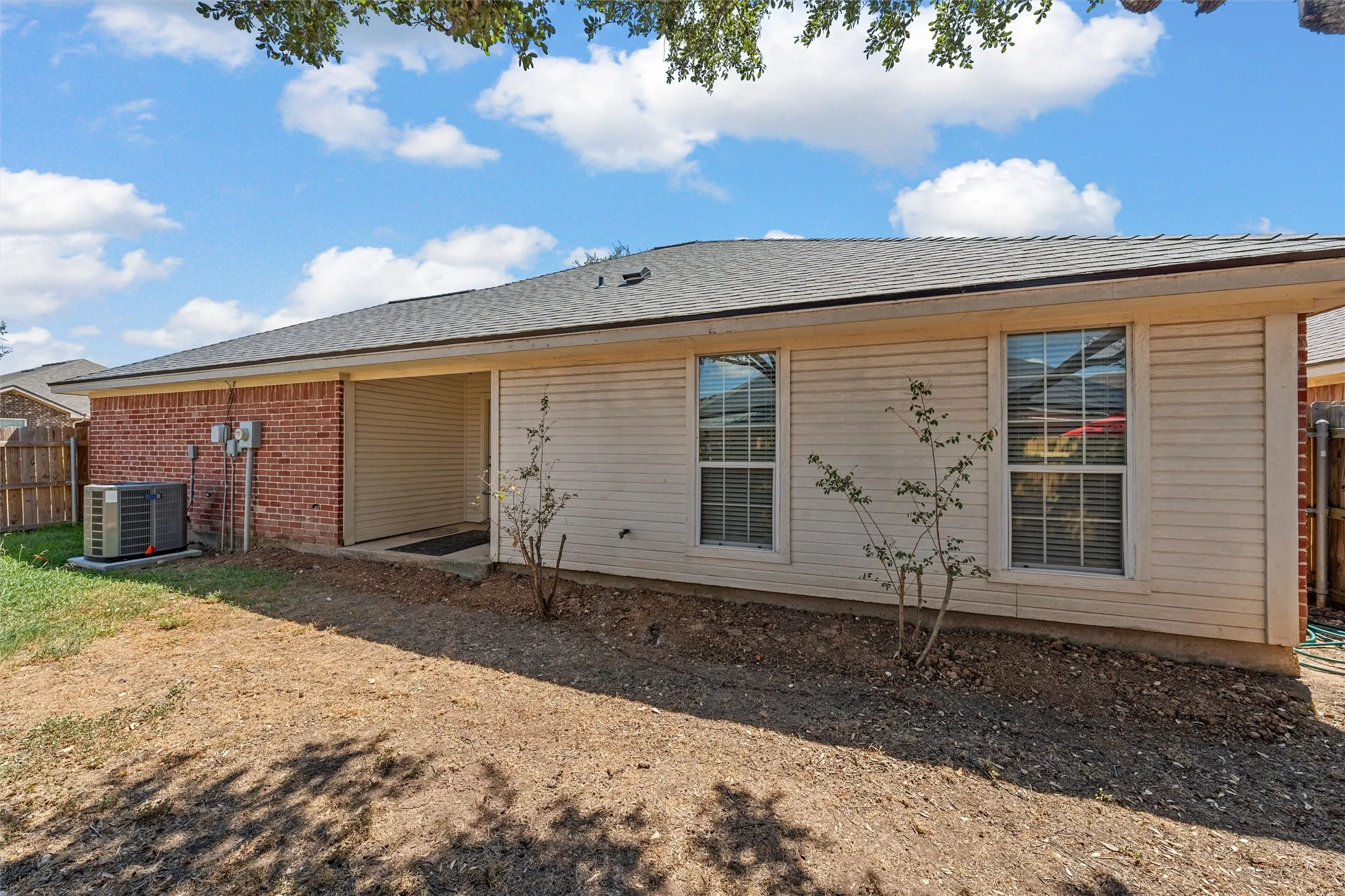Exterior featuring brick and horizontal siding, with multiple windows and a covered entrance