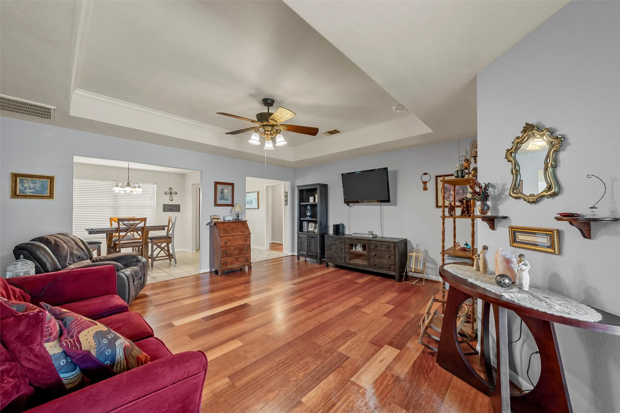Hardwood-finish flooring, tray ceiling with crown molding, ceiling fan with integrated lighting, recessed wall opening