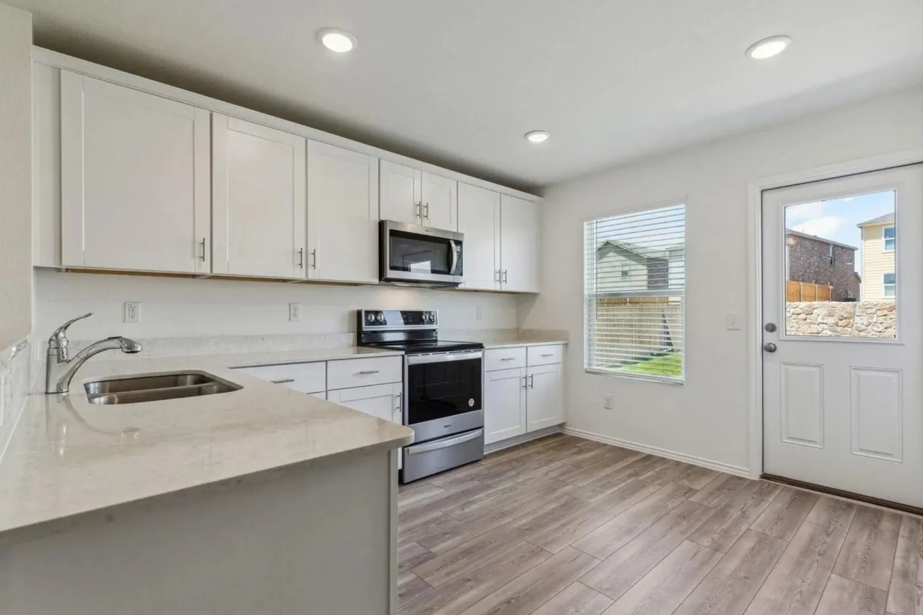 Kitchen featuring wood-finish flooring, recessed lighting, white cabinetry, stainless steel appliances, and light-toned countertops