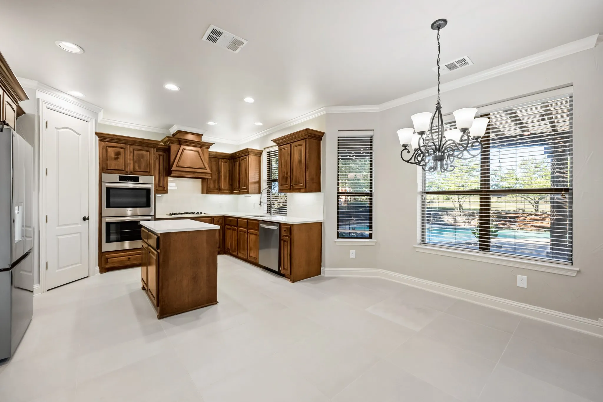 Newly remodled kitchen features room for a breakfast table, double ovens, under cabinet lighting, gas cooktop, and vent hood.