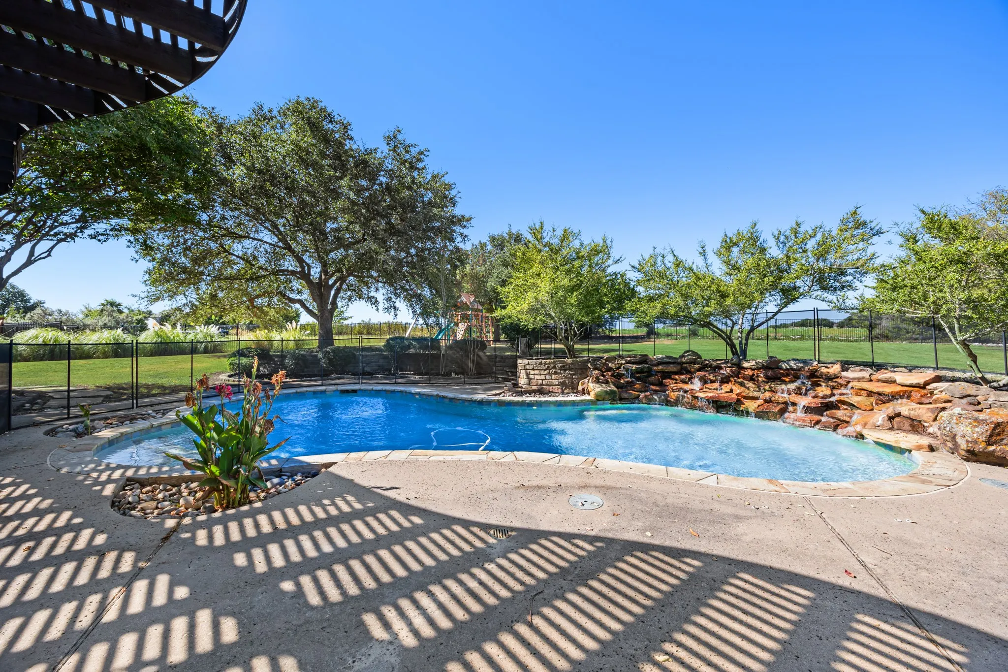 Pool with waterfall feature and a safety fence