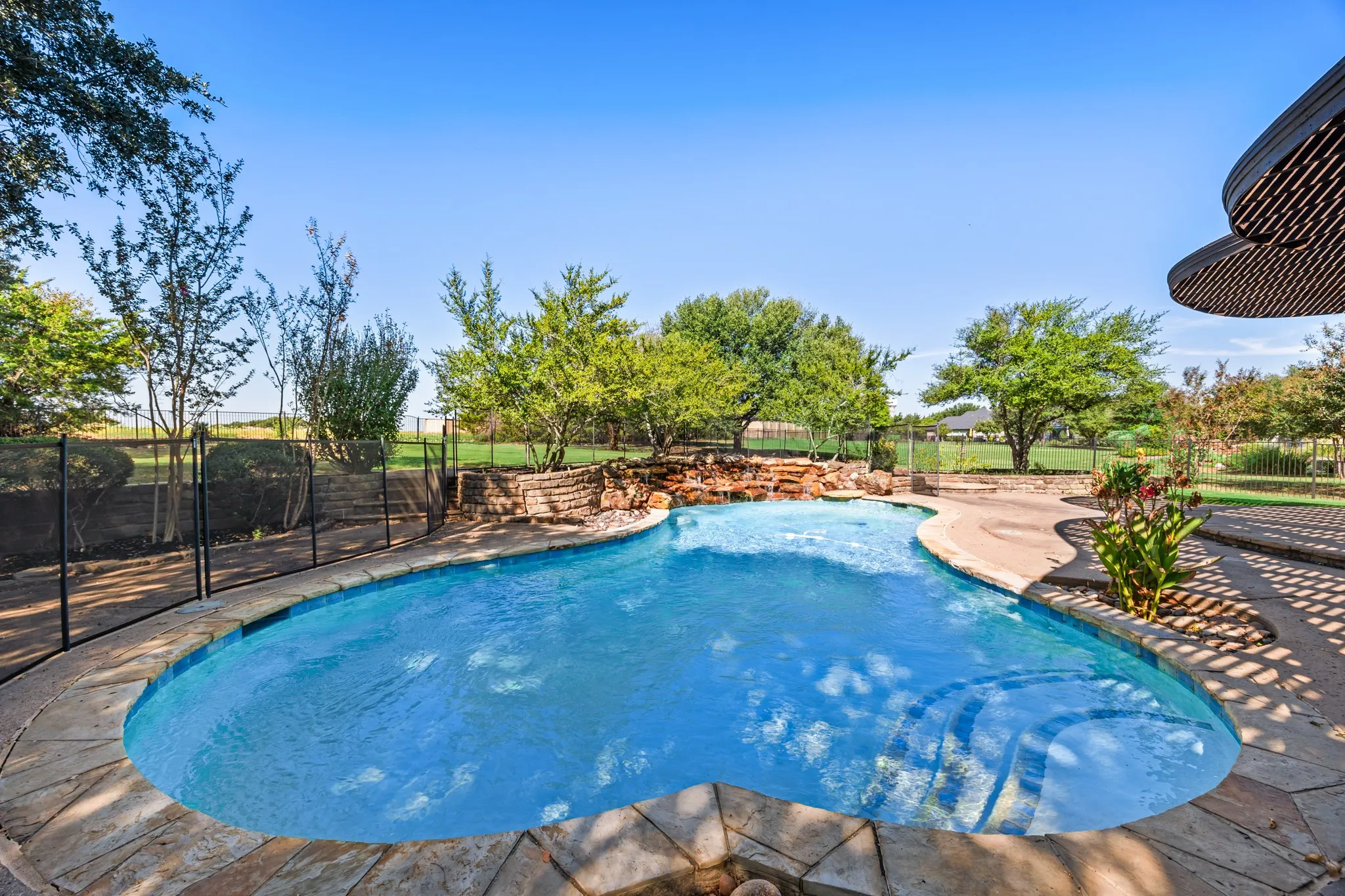 Sparkling pool with waterfall feature and safety fence