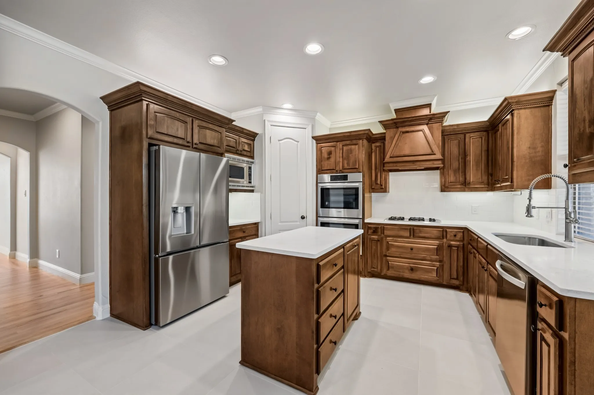 Newly remodled kitchen features room for a breakfast table, double ovens, under cabinet lighting, gas cooktop, and vent hood.