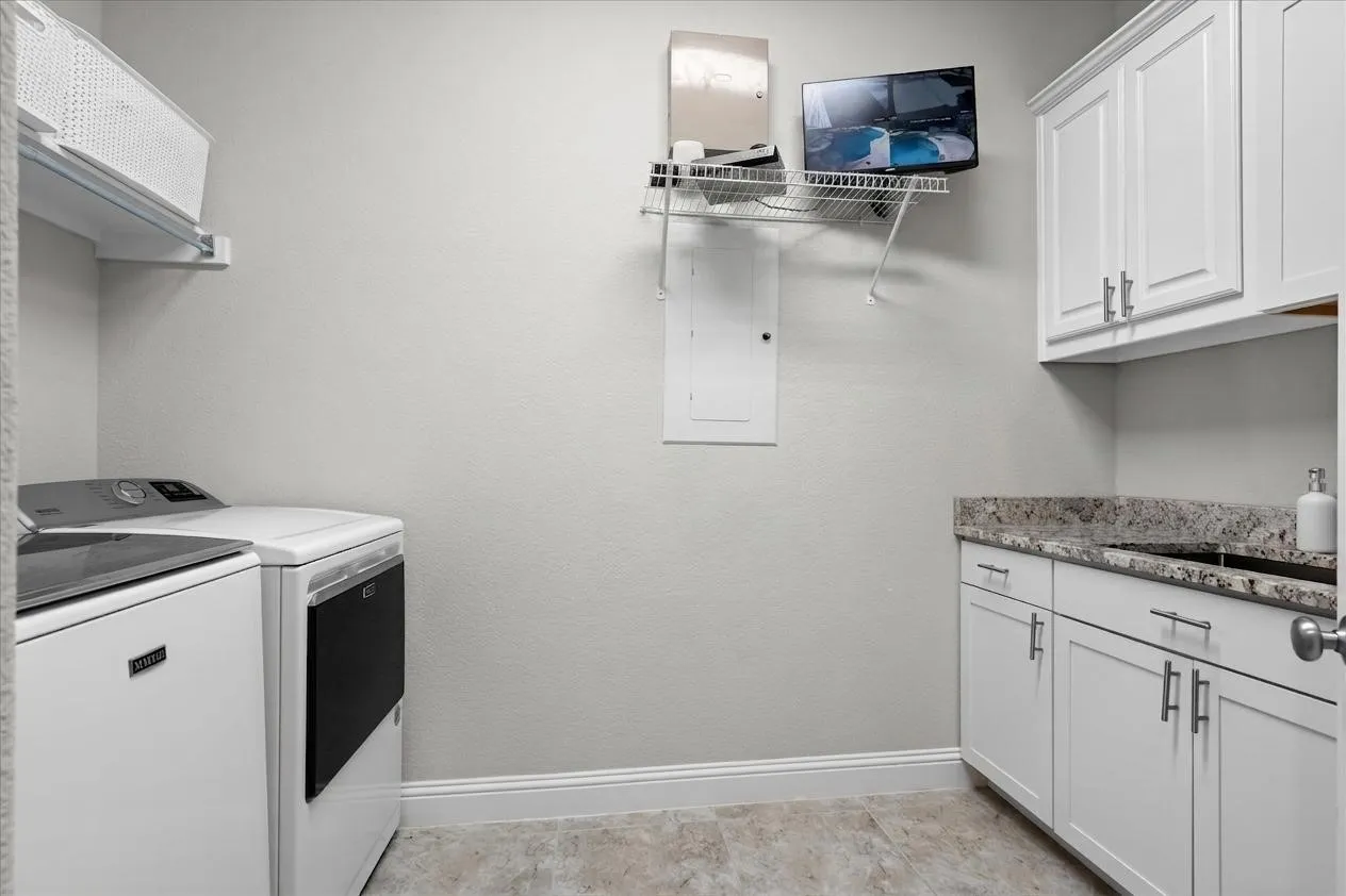 A dedicated laundry room with built-in cabinetry, granite-look counter space, and storage.