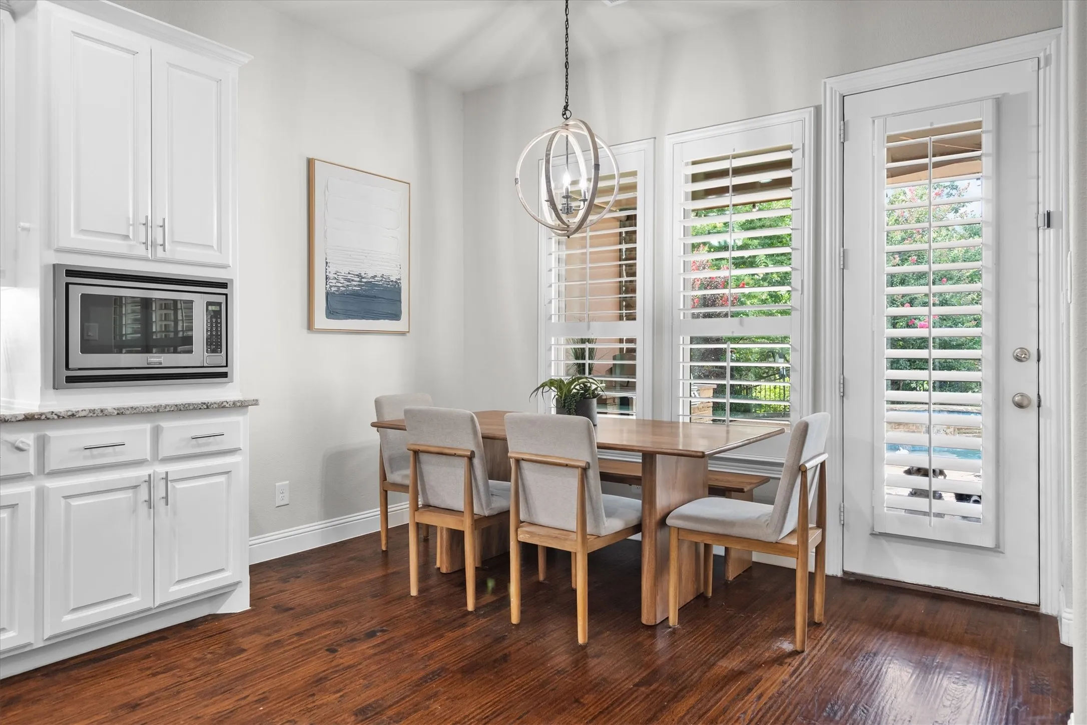  A casual dining space with plantation shutters, built-in serving cabinetry, and direct backyard access.