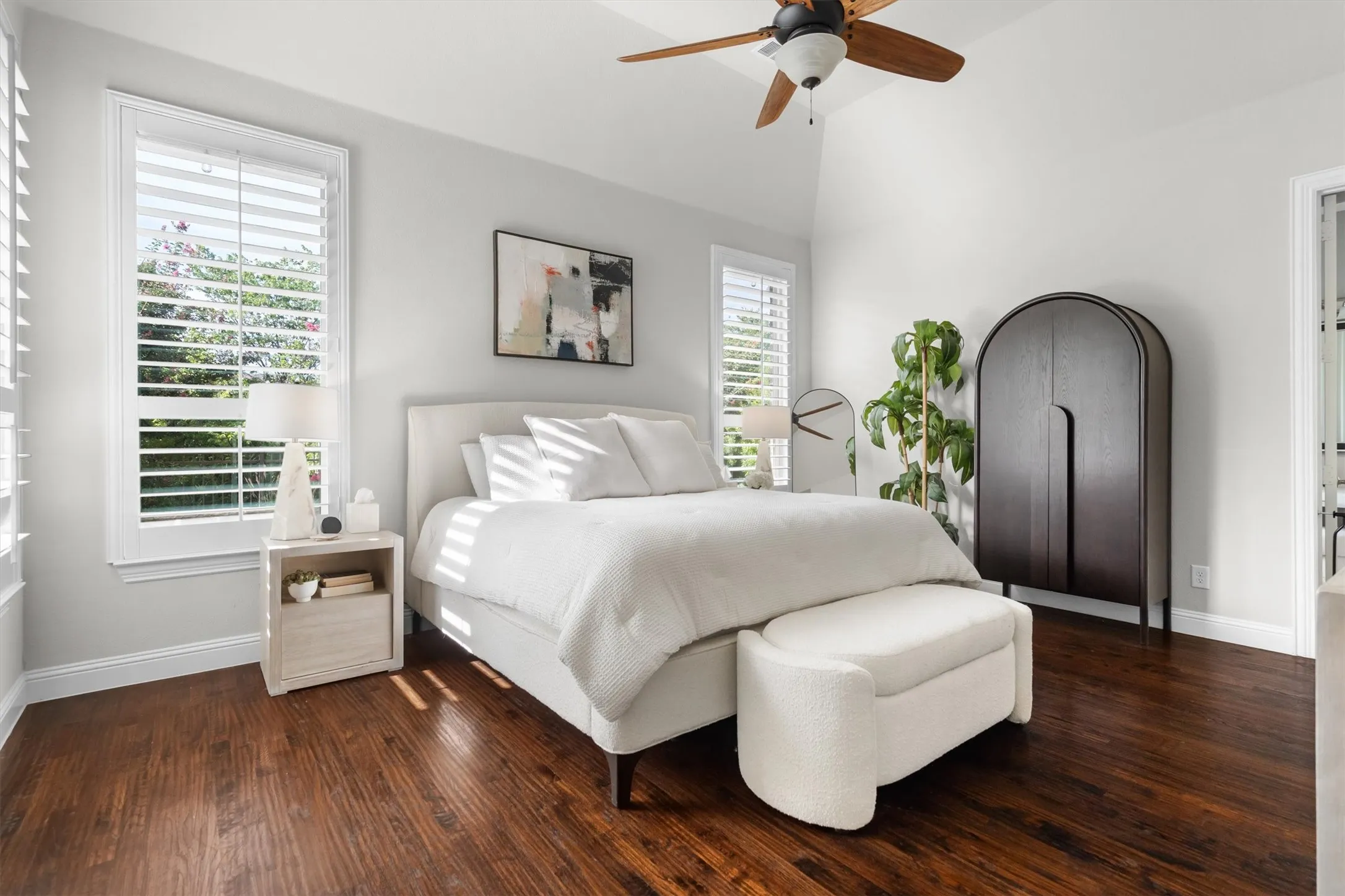 A bright, spacious primary retreat with hardwood floors, ceiling fan, and elegant natural light.