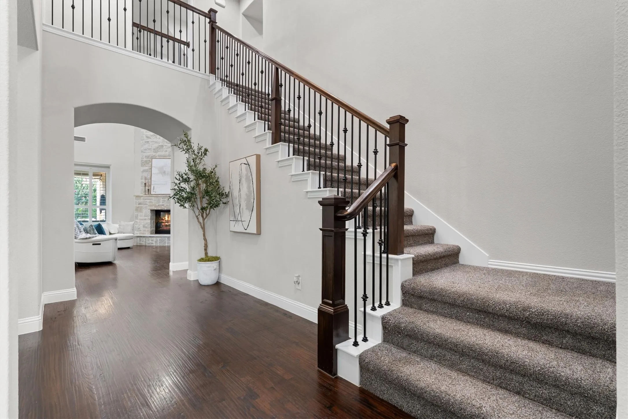 An elegant curved staircase with wrought-iron balusters and wood treads rises from the main living area.