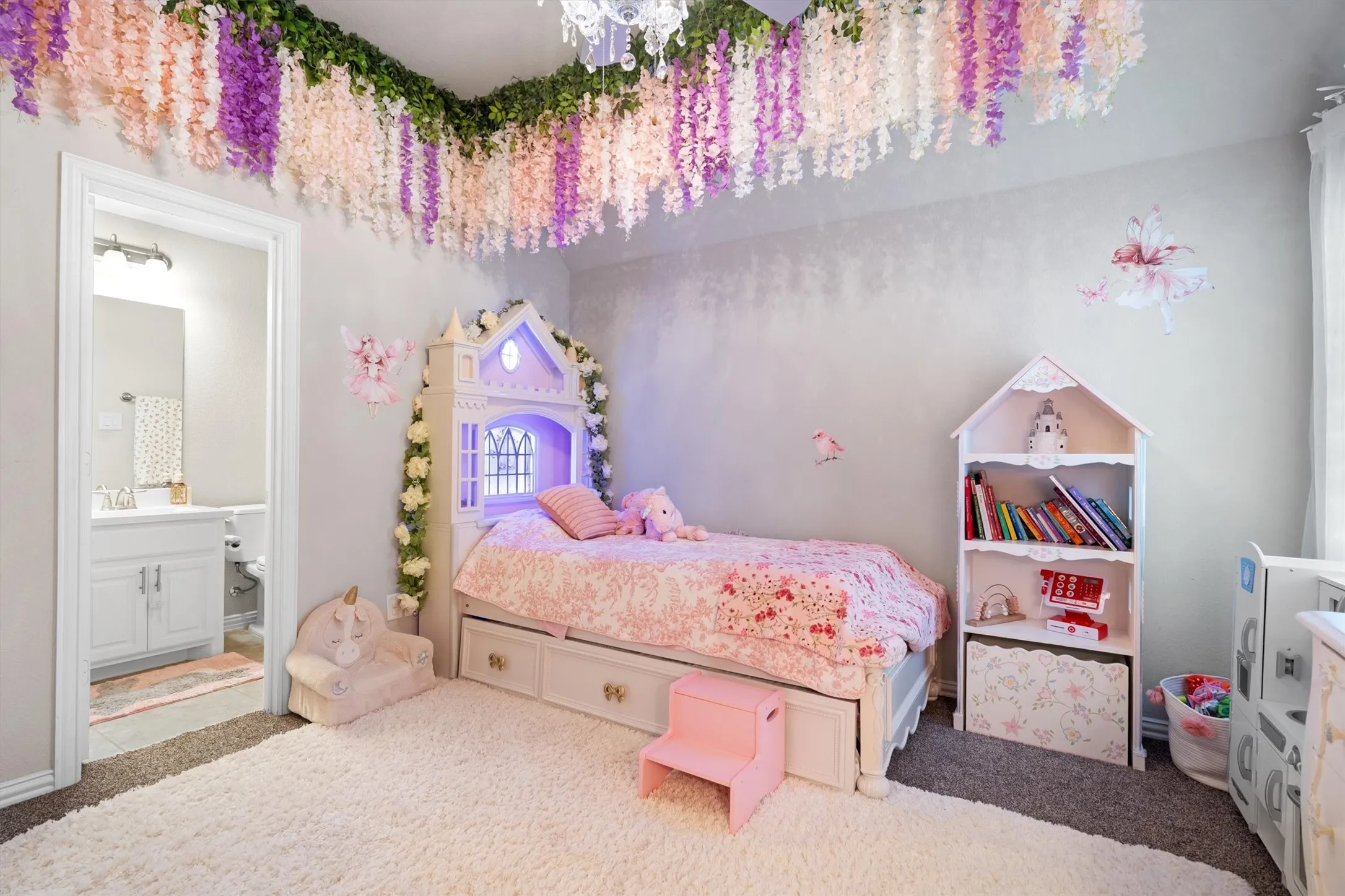 A darling bedroom with decorative canopy detail, built-in storage bed, and adjoining bath access.